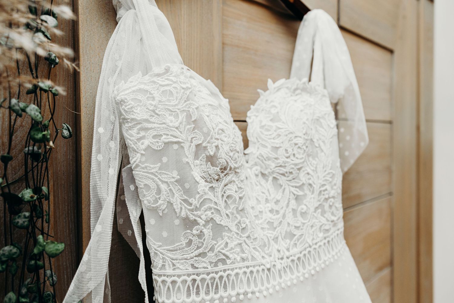 Detail shot of intricate lace pattern on a white wedding dress bodice.