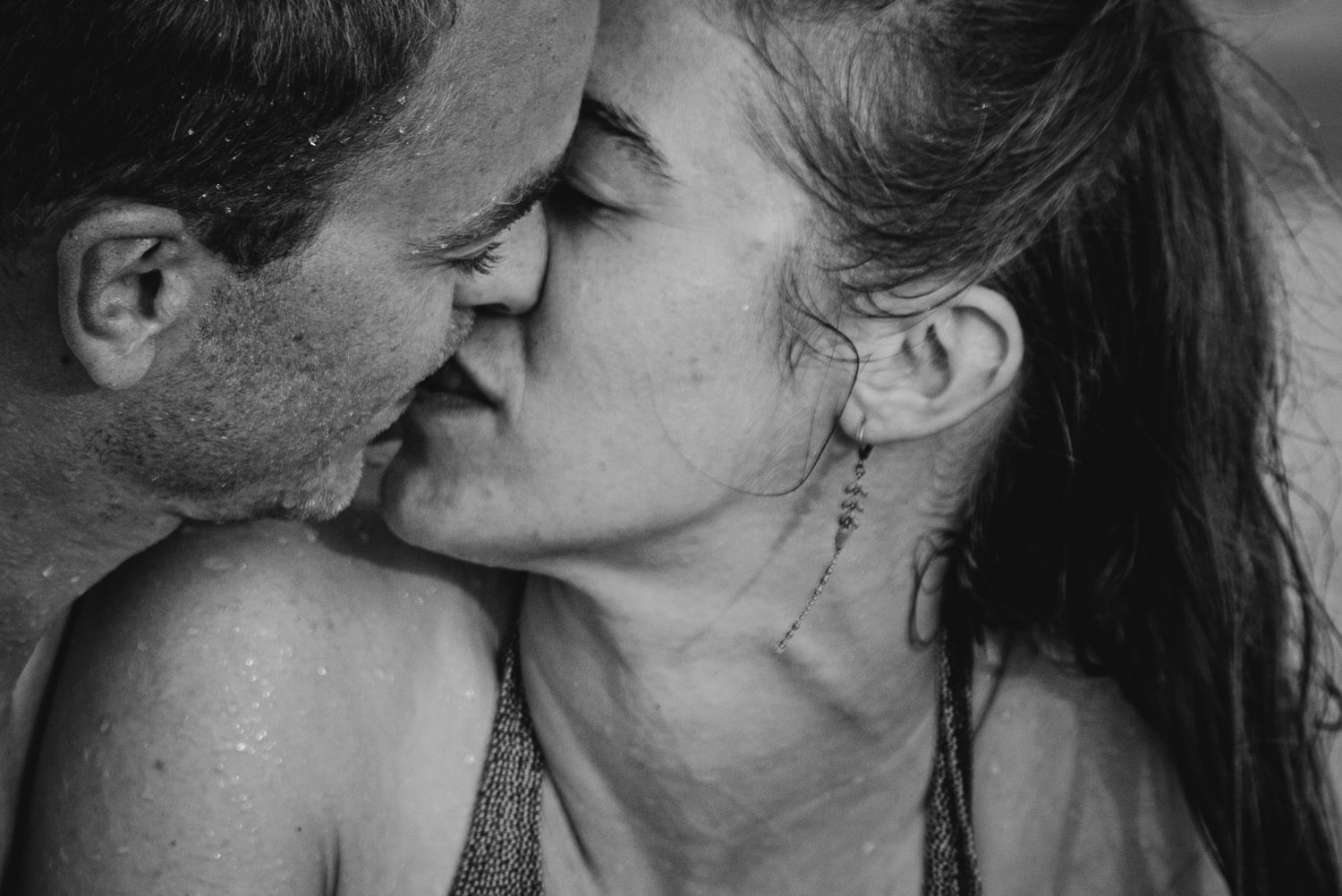 A black and white photo collage showing five intimate close-up shots of couples kissing.