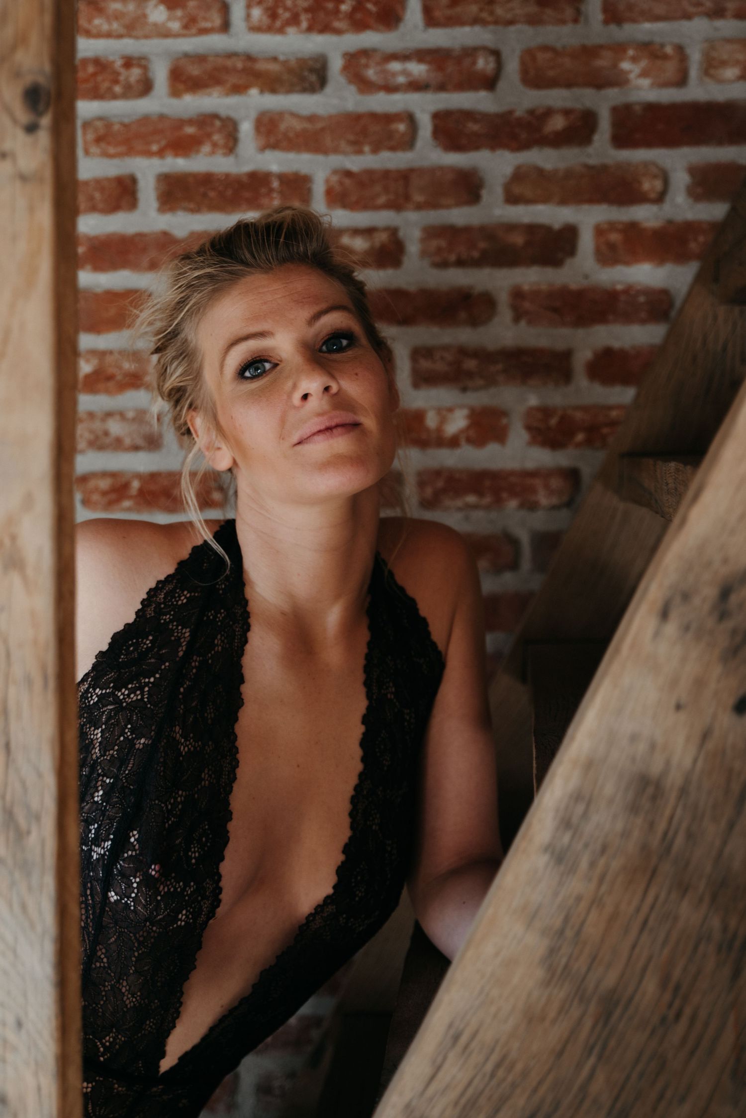 A dramatic portrait against a brick wall background featuring a black sequined dress and artistic pose.