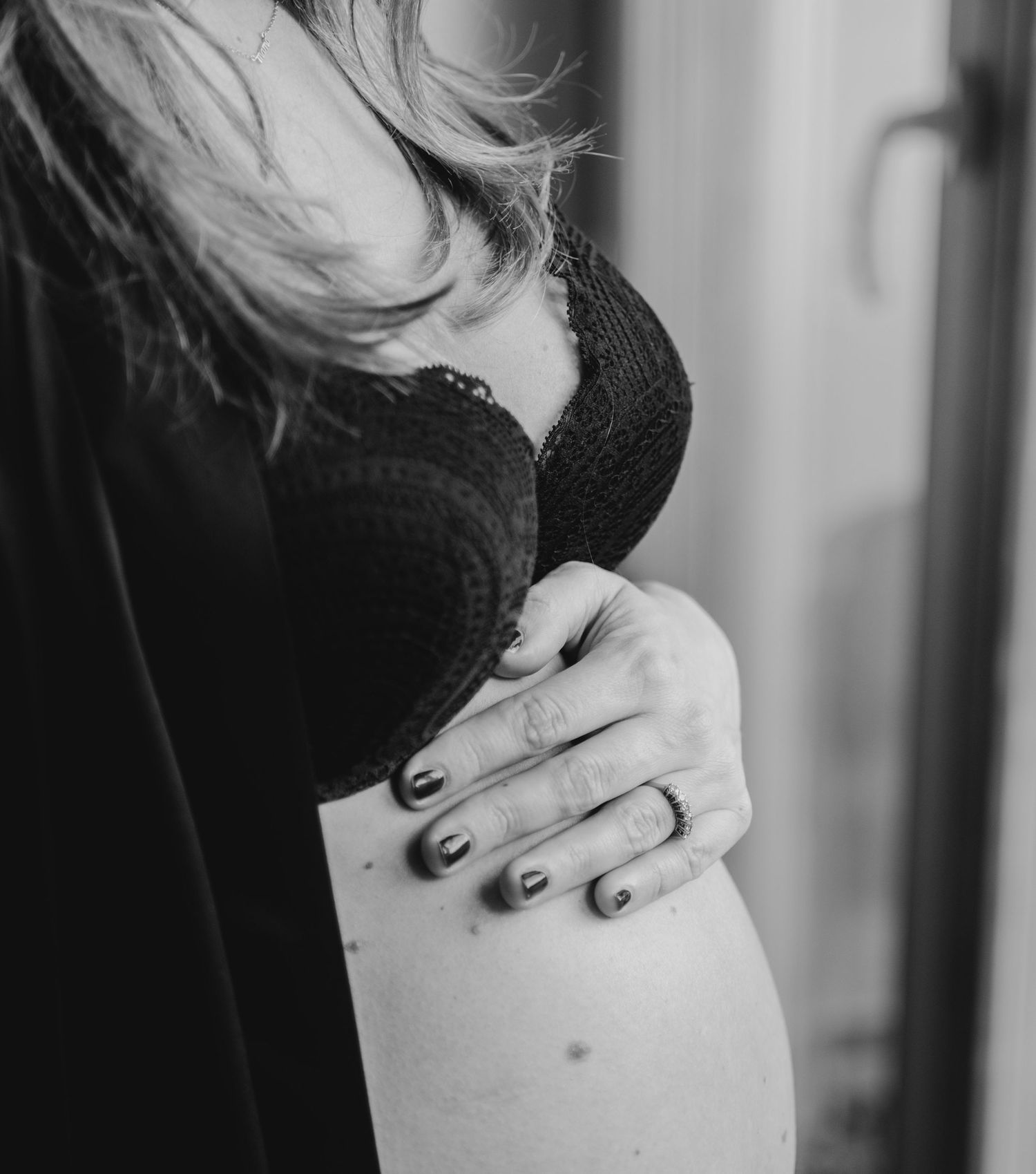 A person gently massages their neck and shoulder area while wearing a black top in a series of monochrome photos.