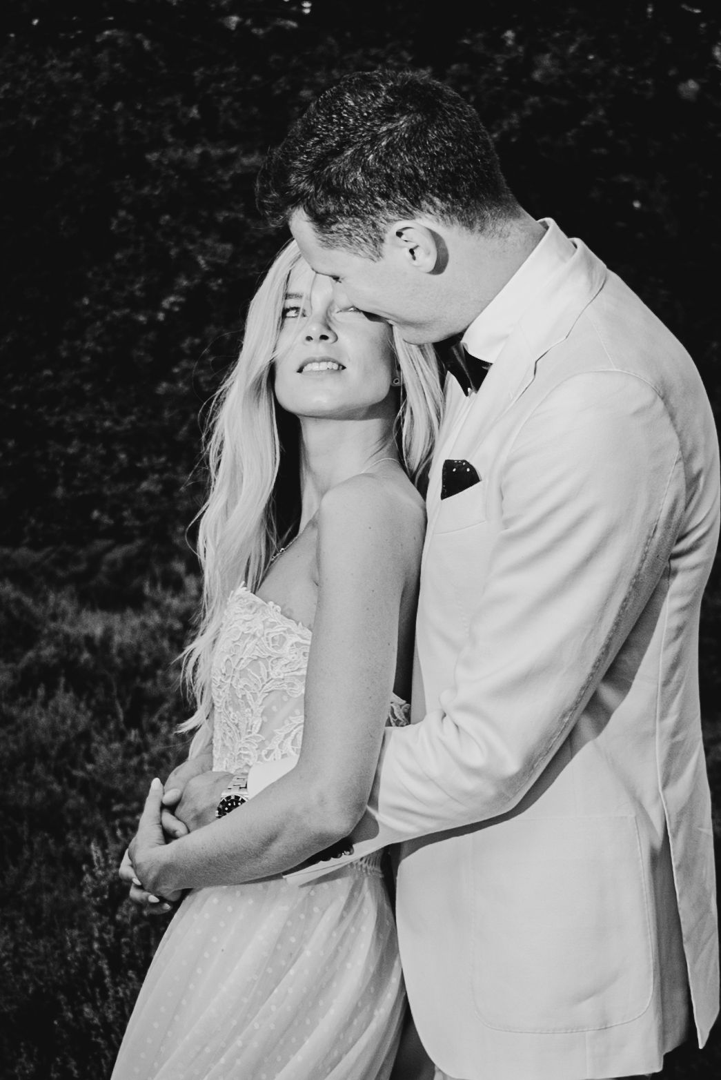 Black and white intimate portrait of a couple in formal wedding attire.