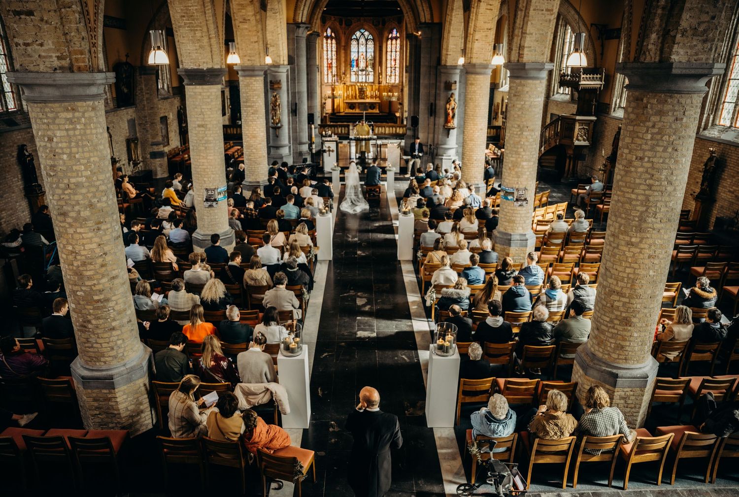Interior of a historic church filled with wedding guests during a ceremony.