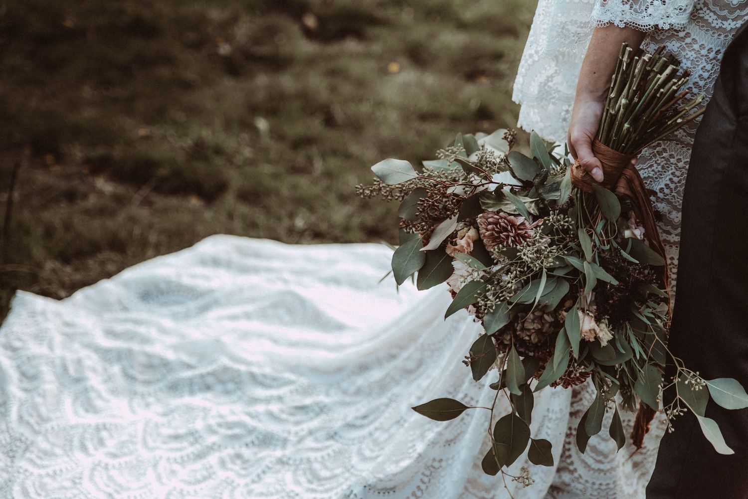 Delicate white lace wedding dress detail with floral embroidery in natural lighting.