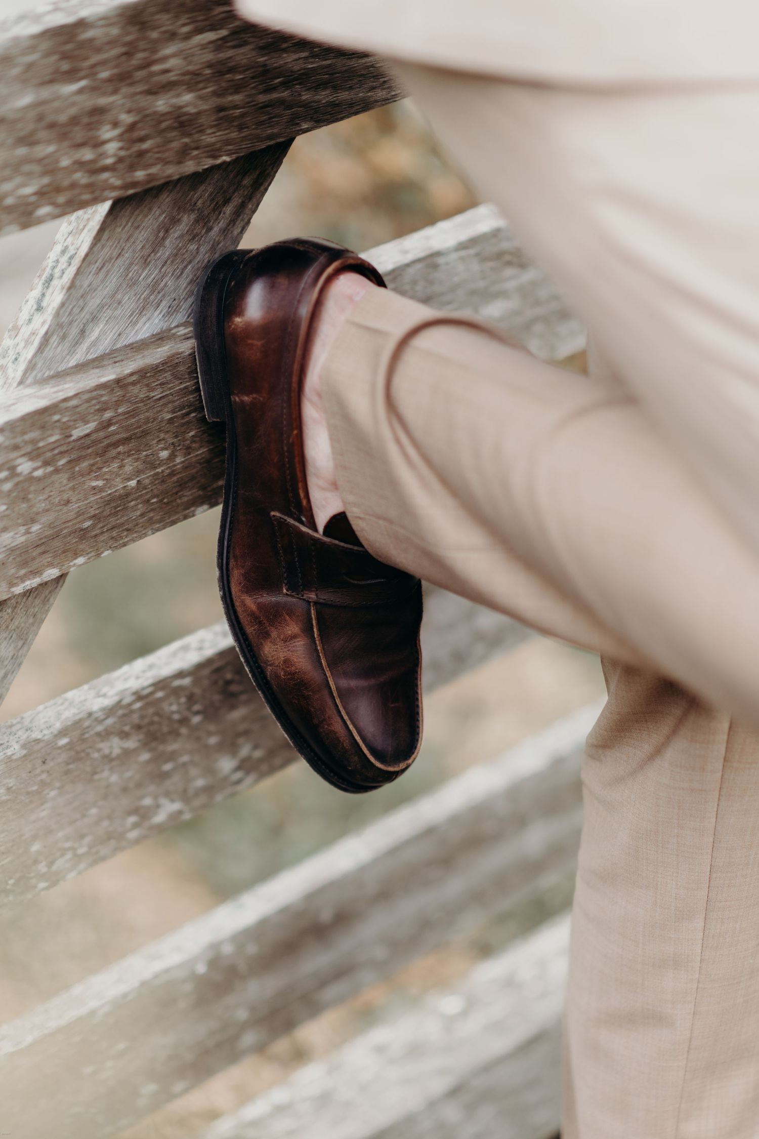 Close-up of polished brown leather dress shoes with light colored formal pants.