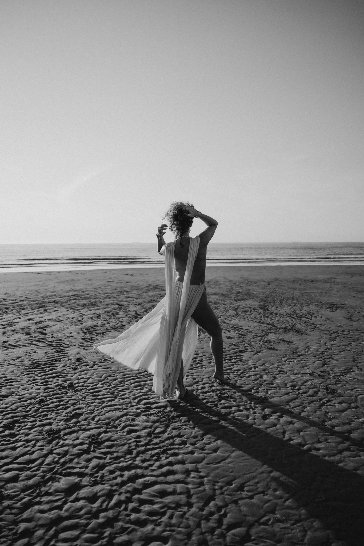 A series of black and white beach photos showing silhouettes dancing on textured sand at sunset.