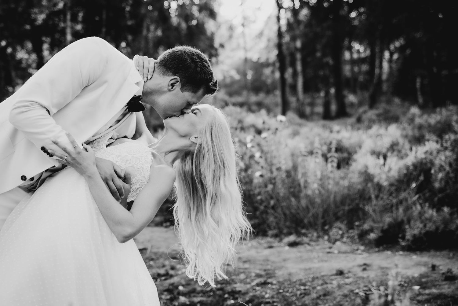 A black and white romantic wedding photo of a couple sharing an intimate moment outdoors.
