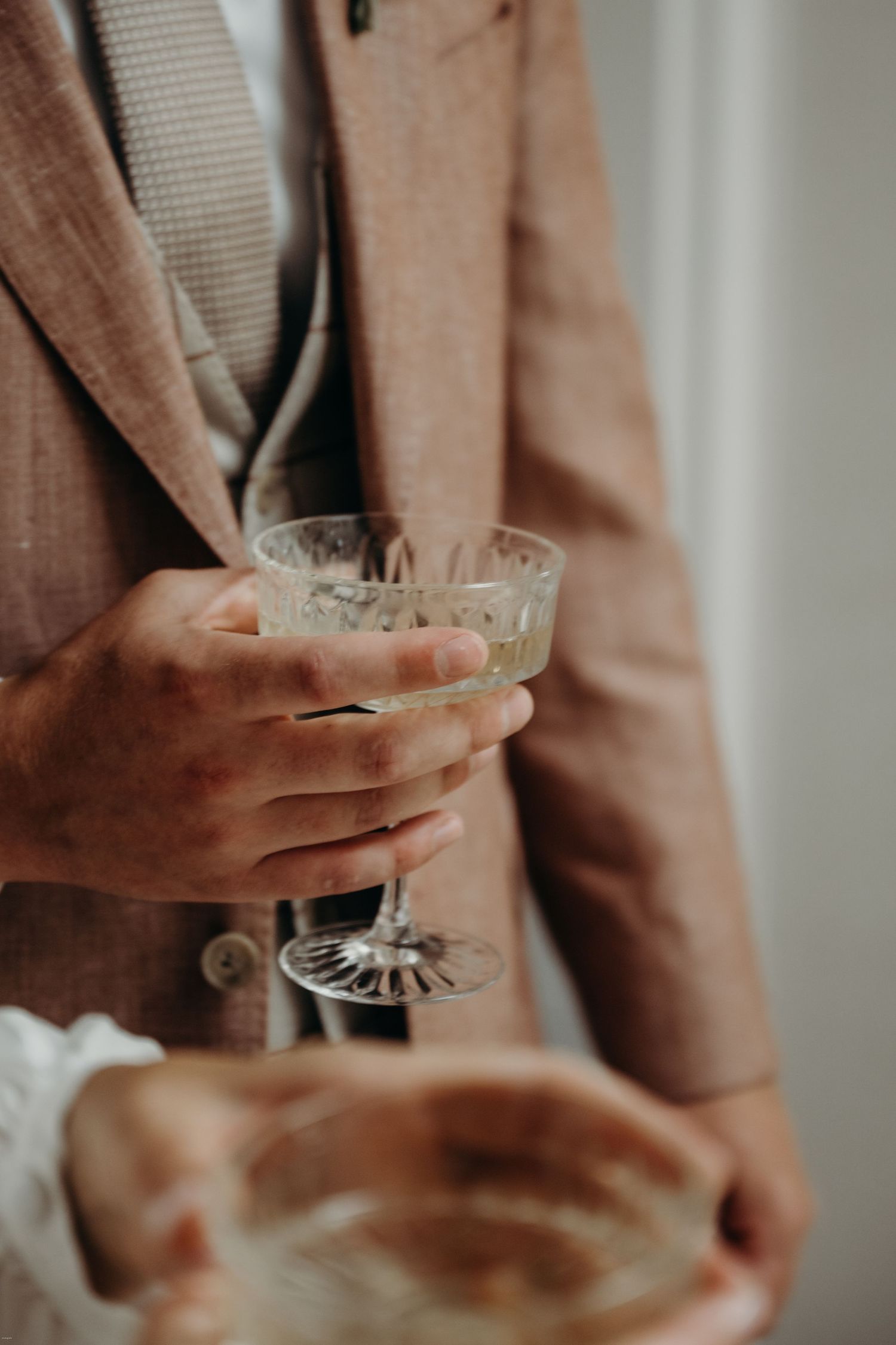 Close-up of hands holding a vintage crystal cocktail glass.