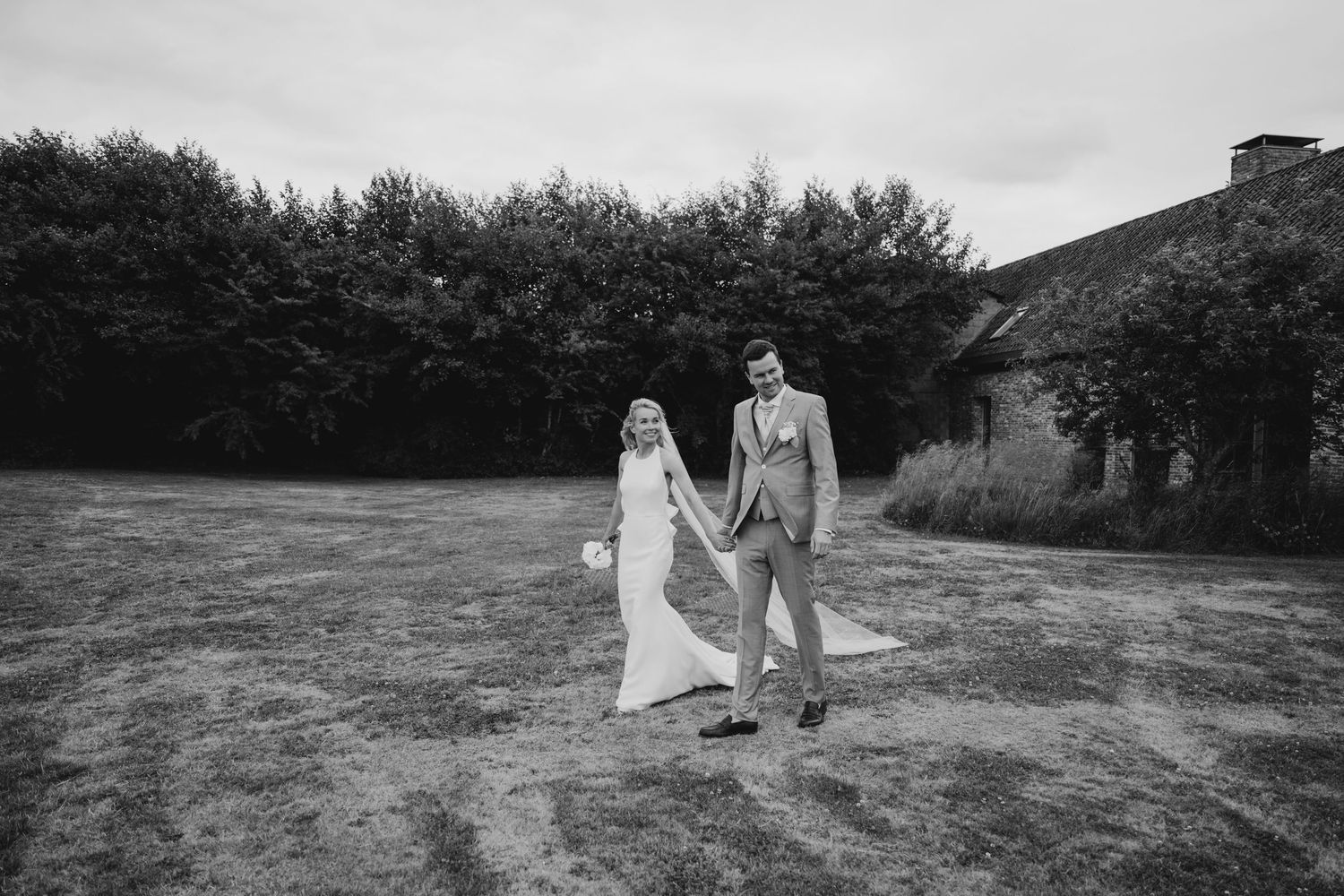 Wedding couple walking through a scenic countryside landscape in black and white.