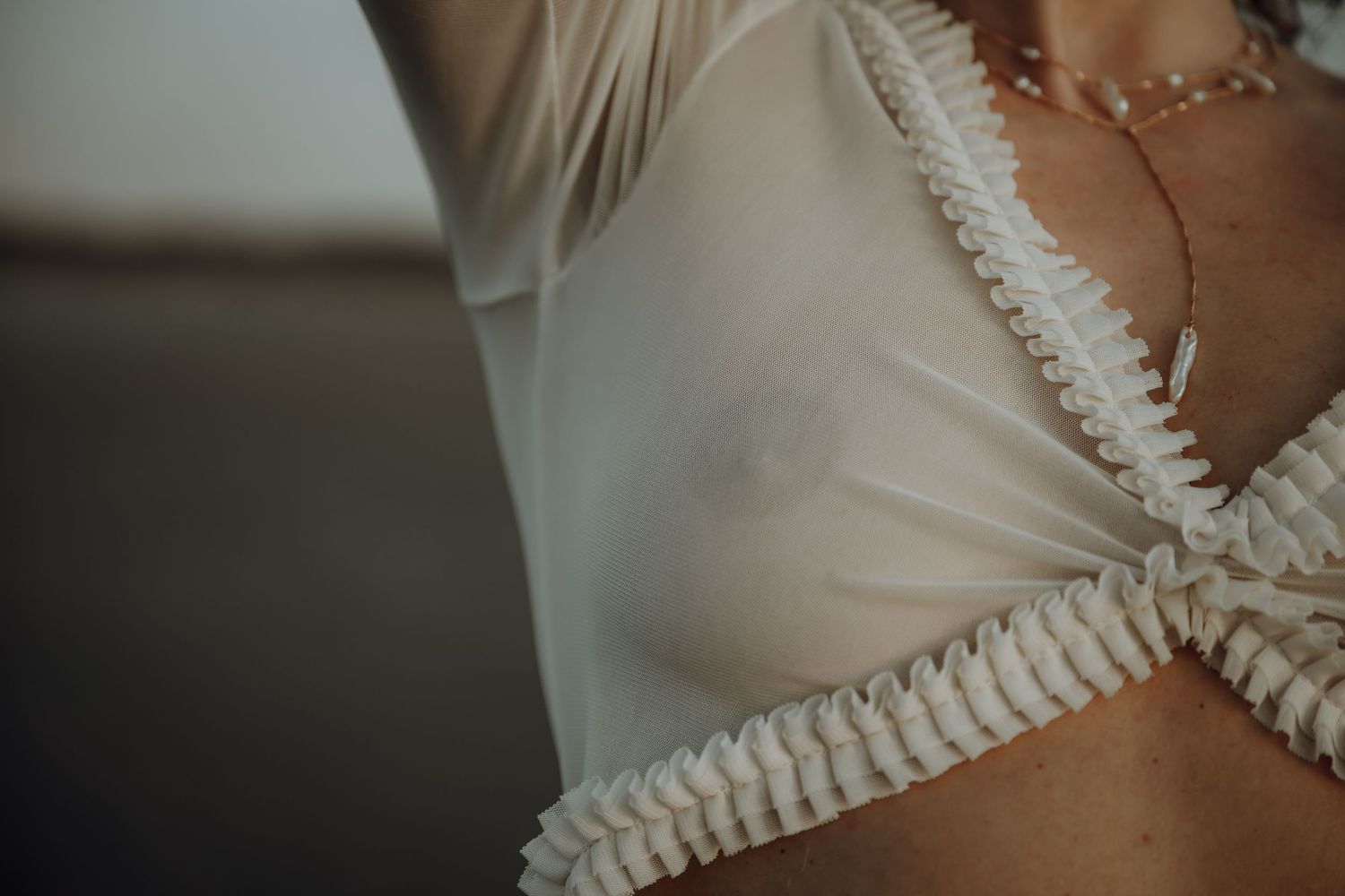 Close-up detail of a white wedding dress bodice with delicate lace trim and ruched fabric details.