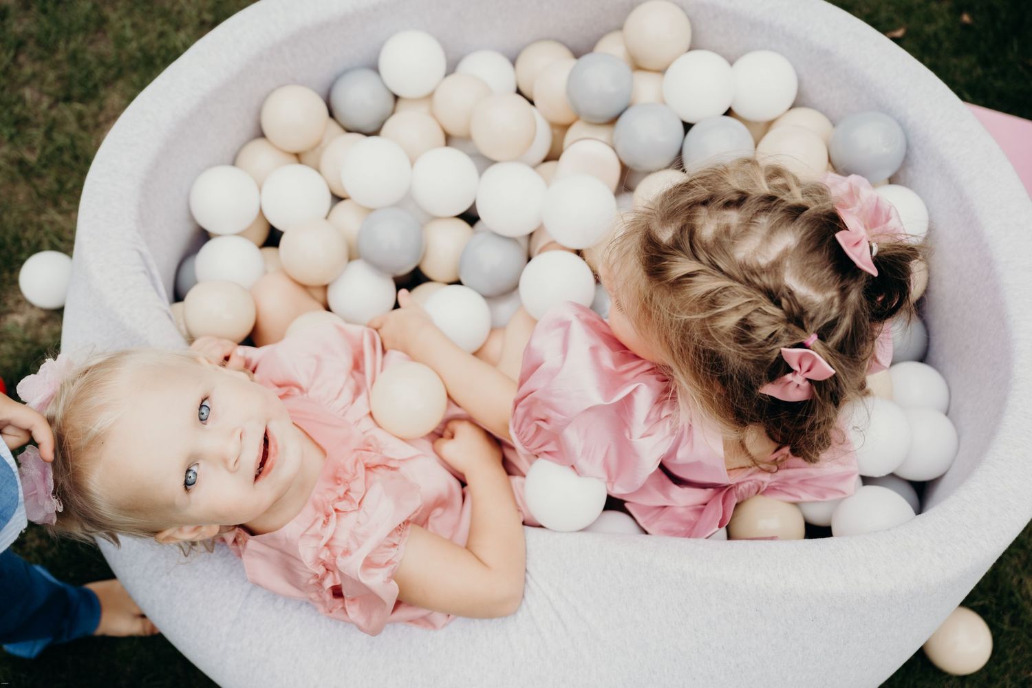 Baby in pink outfit lying in white ball pit for newborn photography session.
