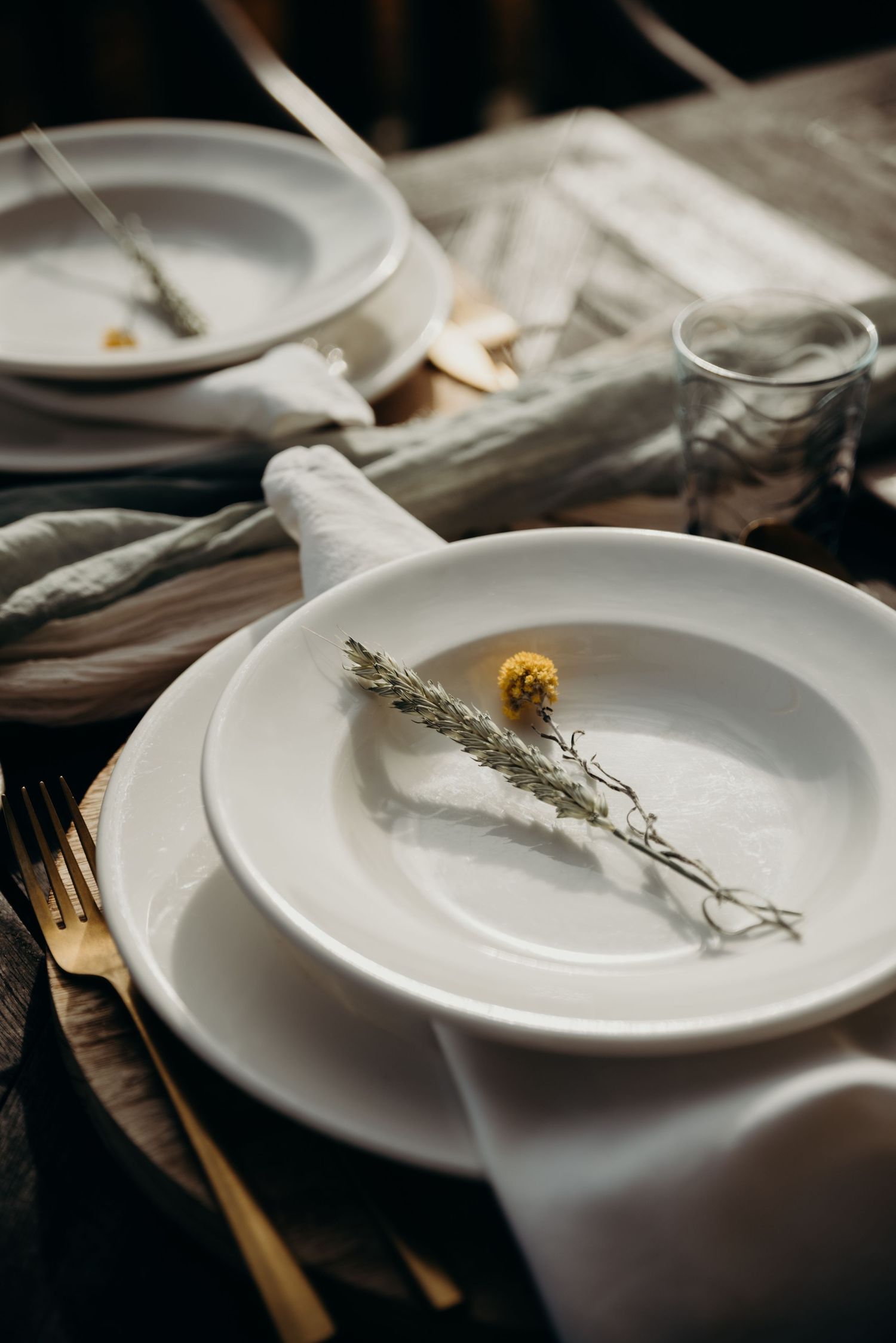 Elegant table settings with white plates and dried herb garnishes in a minimalist style.