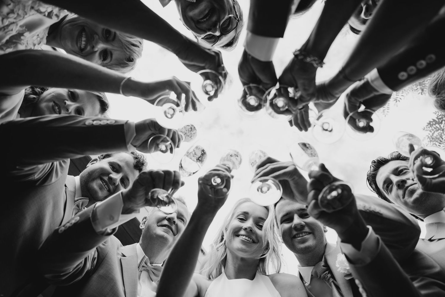 Creative circular group photo looking up at wedding party members wearing sunglasses.