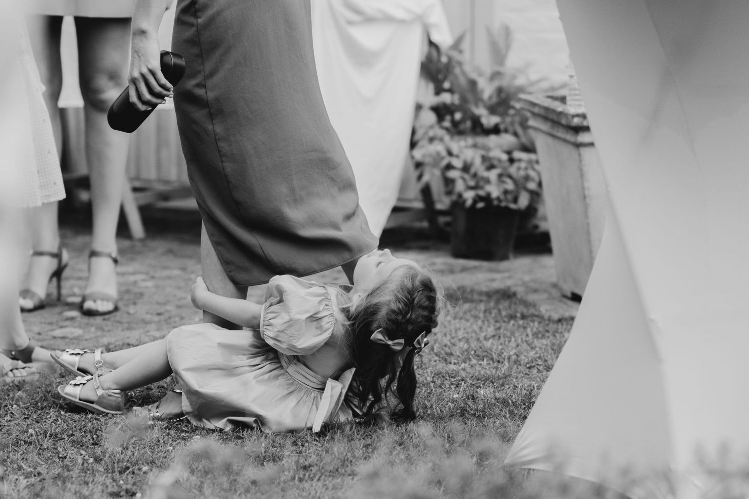 Black and white photo of wedding guests' feet on grass.