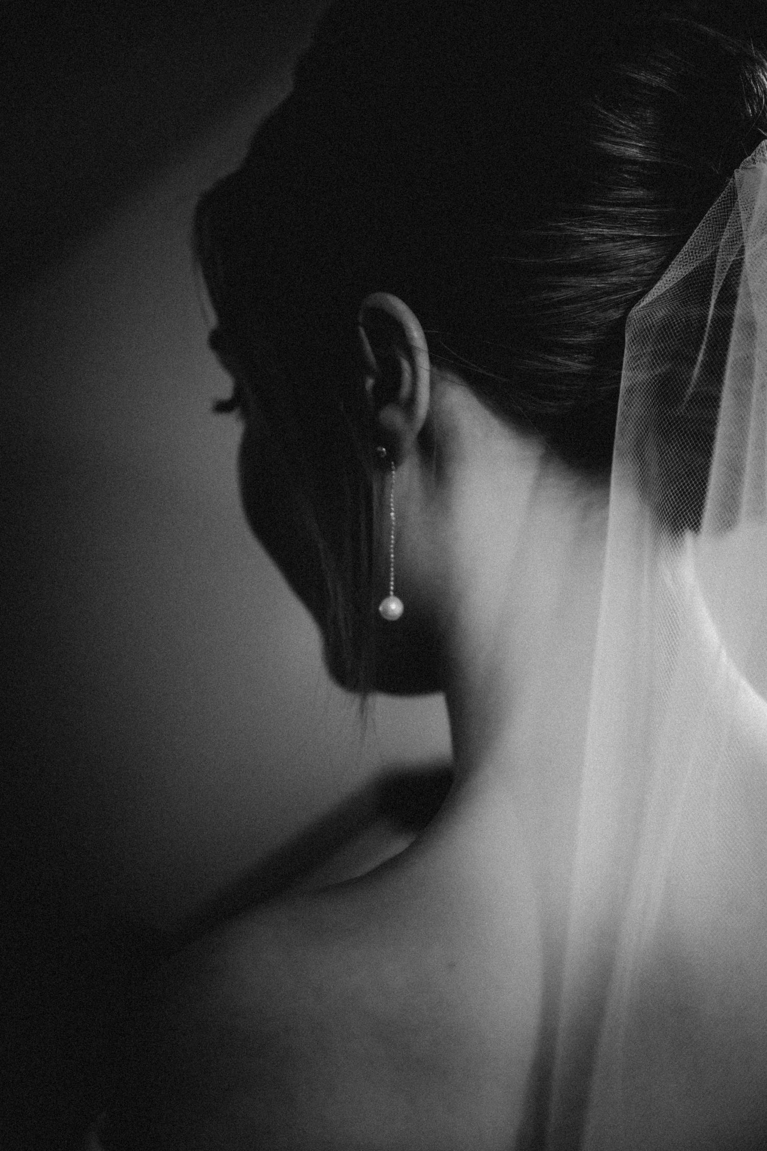 Artistic black and white close-up of a bridal veil and pearl earring.