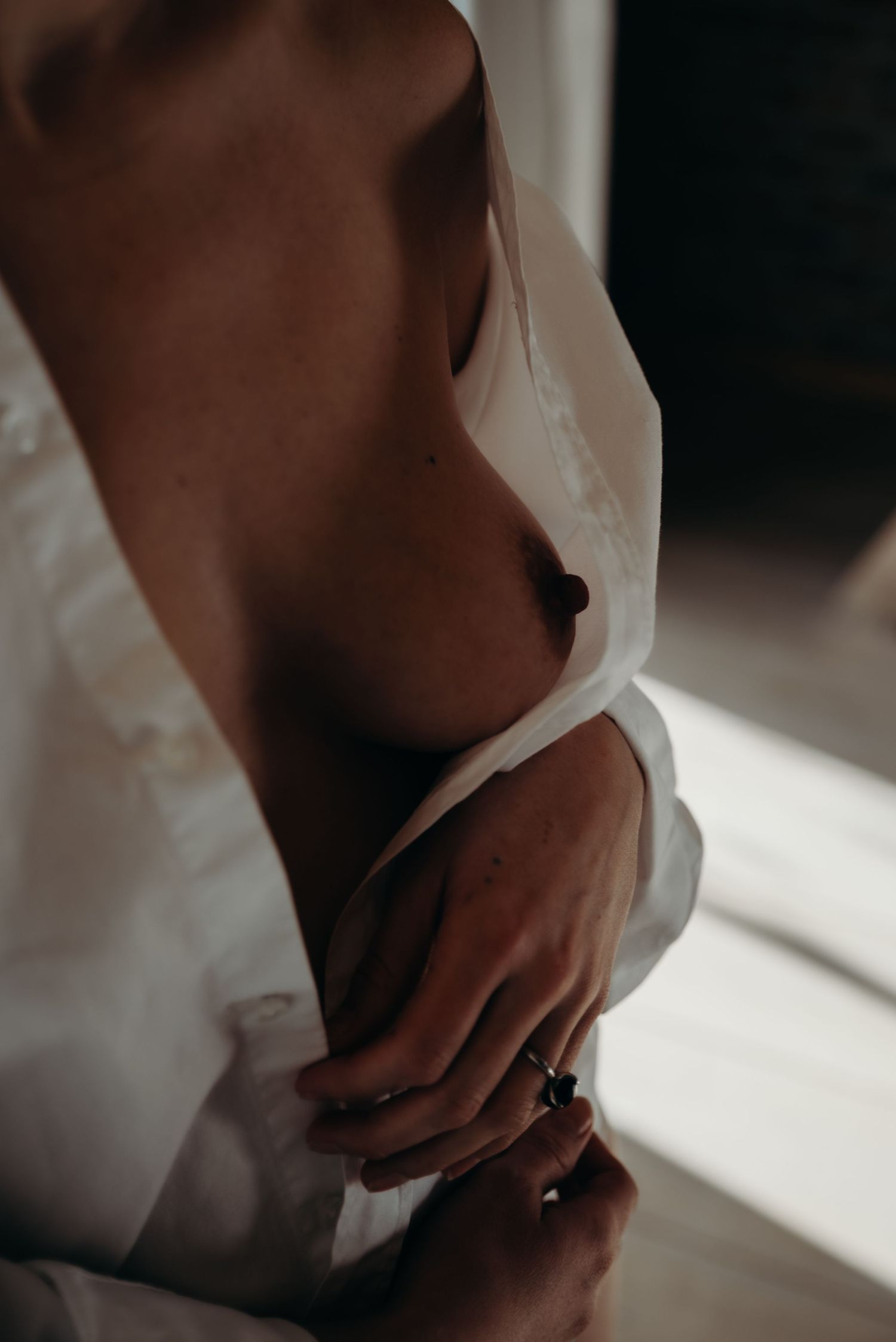Close-up view of hands wearing wedding rings against a light background with soft shadows.