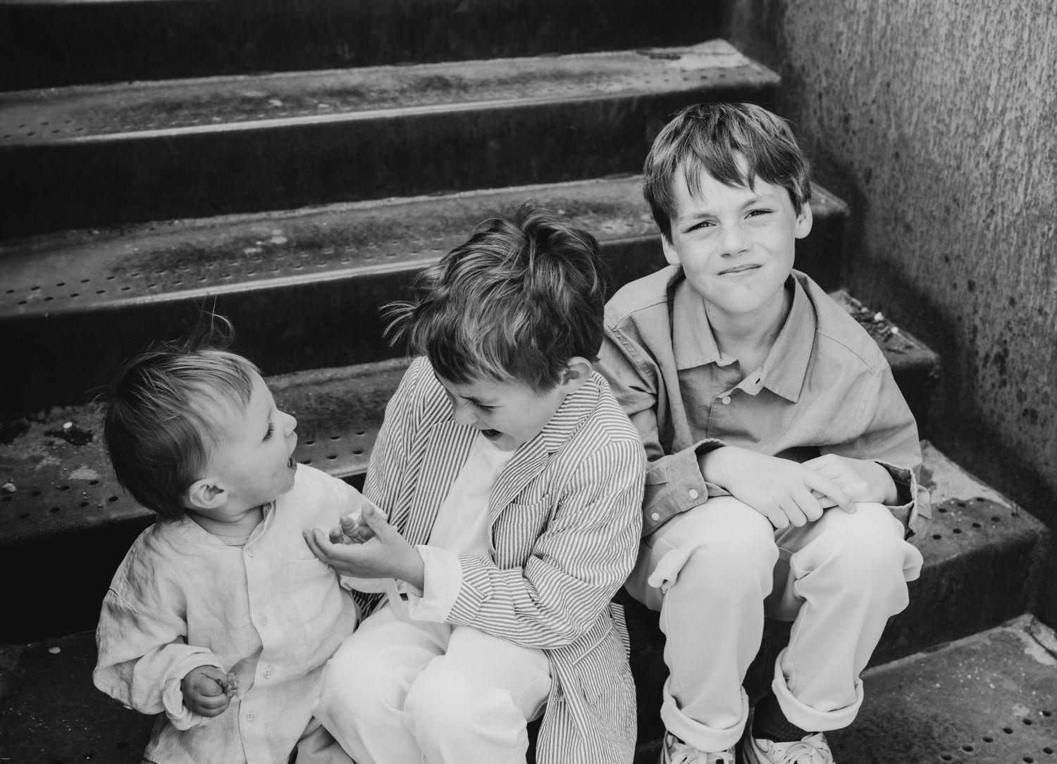 Children sitting together on wooden steps in black and white photograph.