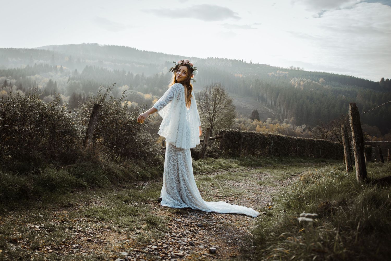 A dreamy mountain landscape serves as the backdrop for an outdoor bridal photoshoot.