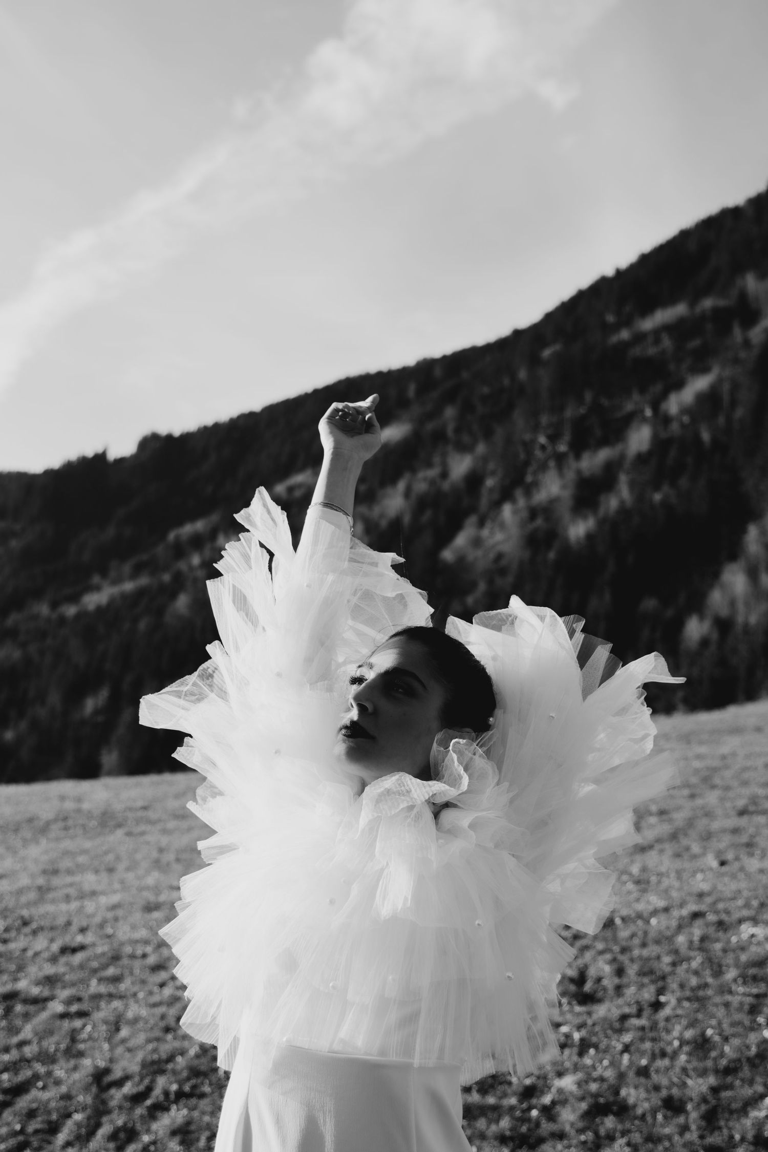White tulle dress fabric flowing against a mountainous black and white landscape.