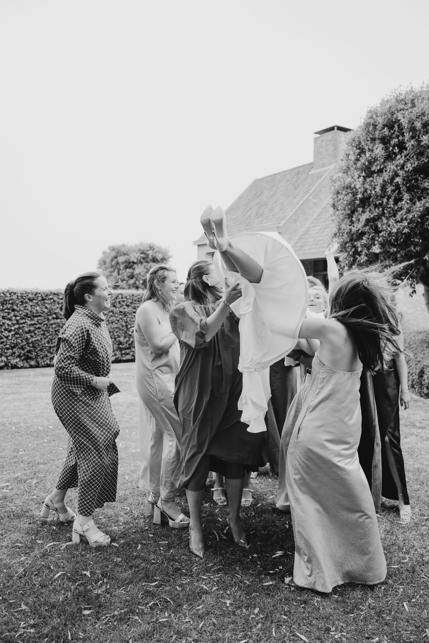 Black and white photo of wedding guests celebrating outdoors near a building.