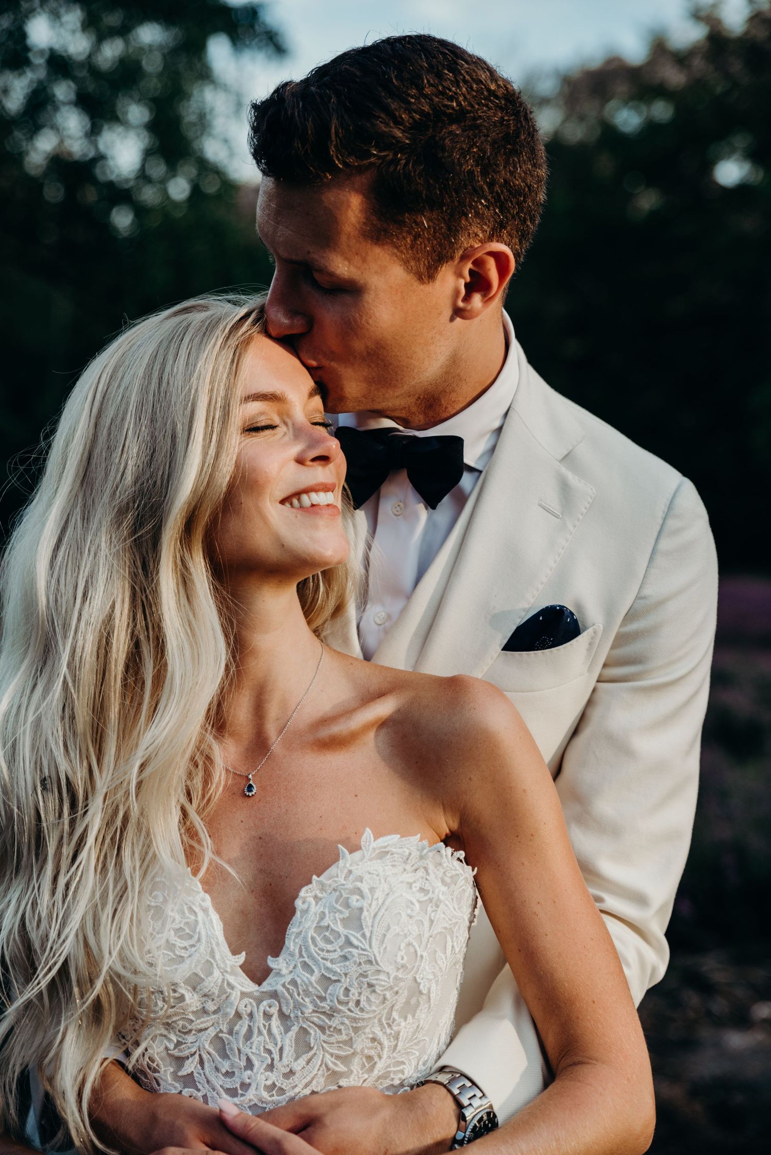 Intimate moment between newlyweds in formal attire during golden hour.