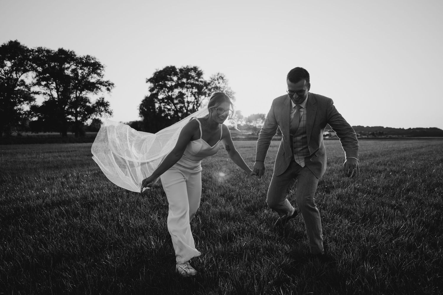 Black and white panoramic shot of couple in field with flowing dress.