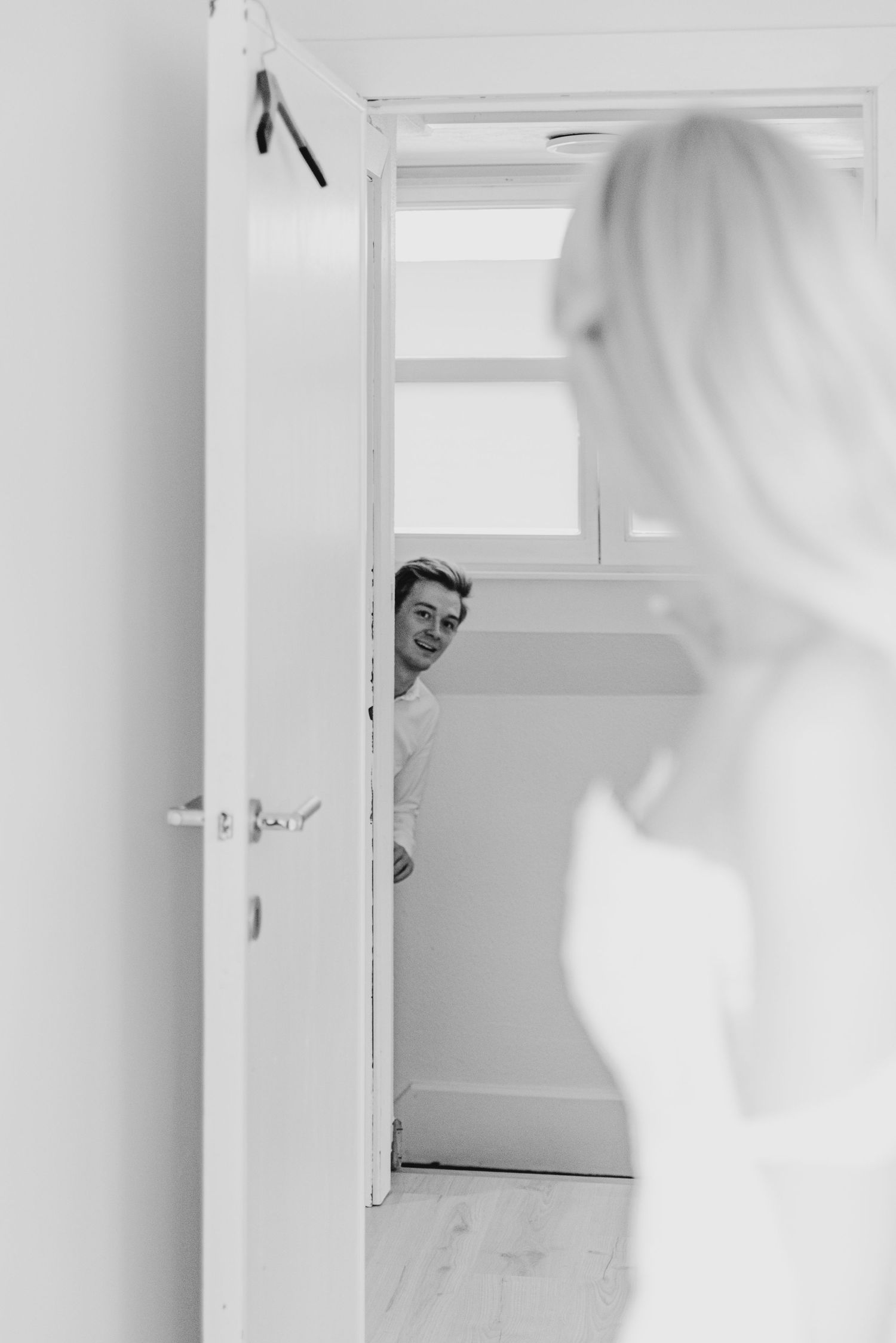 Playful peek-a-boo moment through a white doorway.