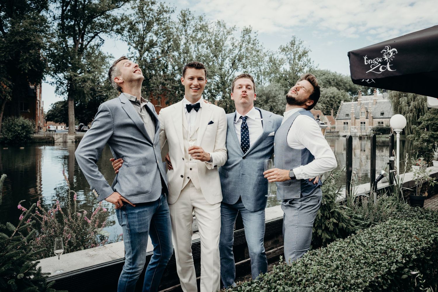 Wedding party members in gray and beige suits posing outdoors.