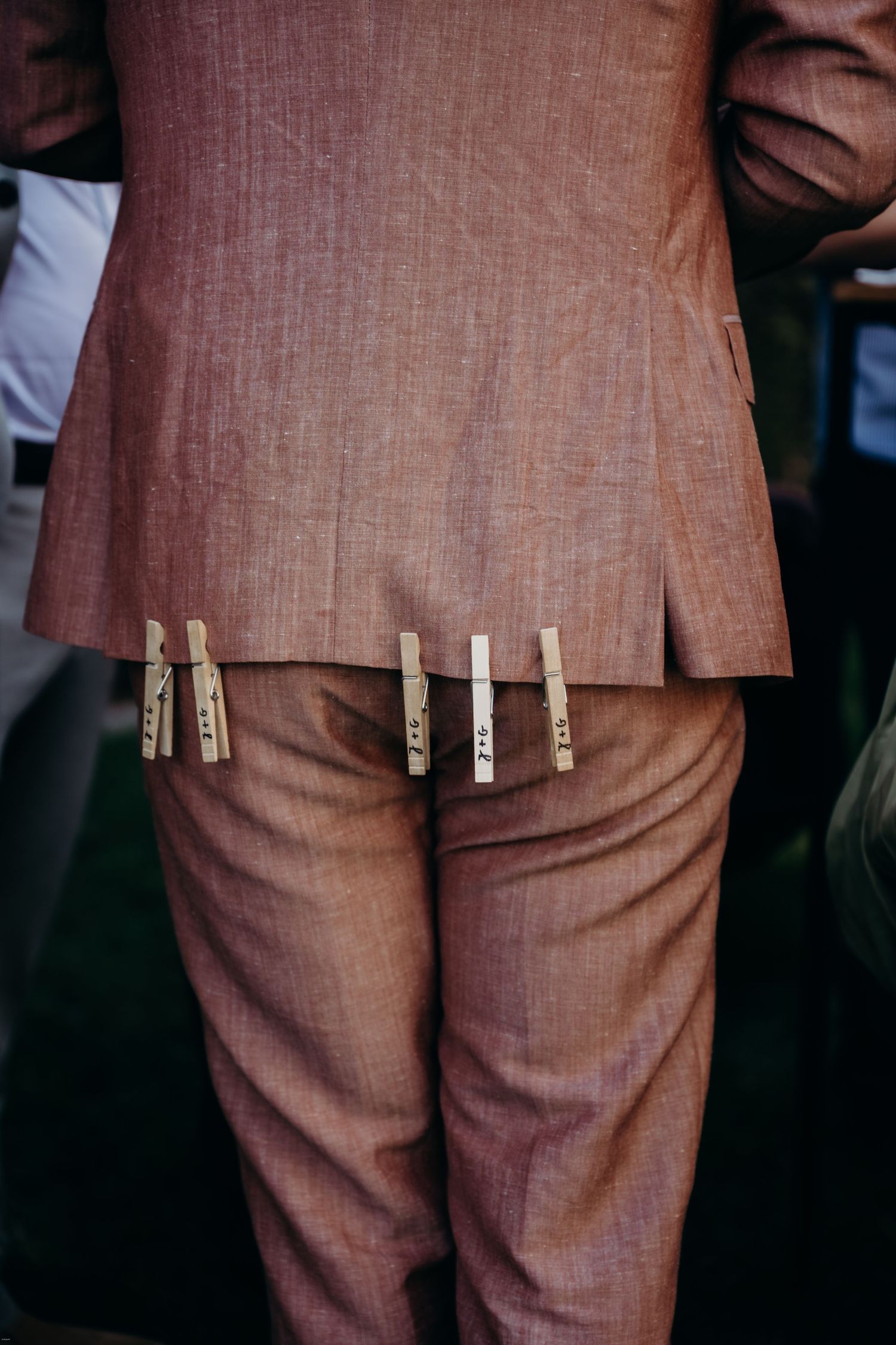 Close-up of wooden clothespins attached to the back of brown formal attire.