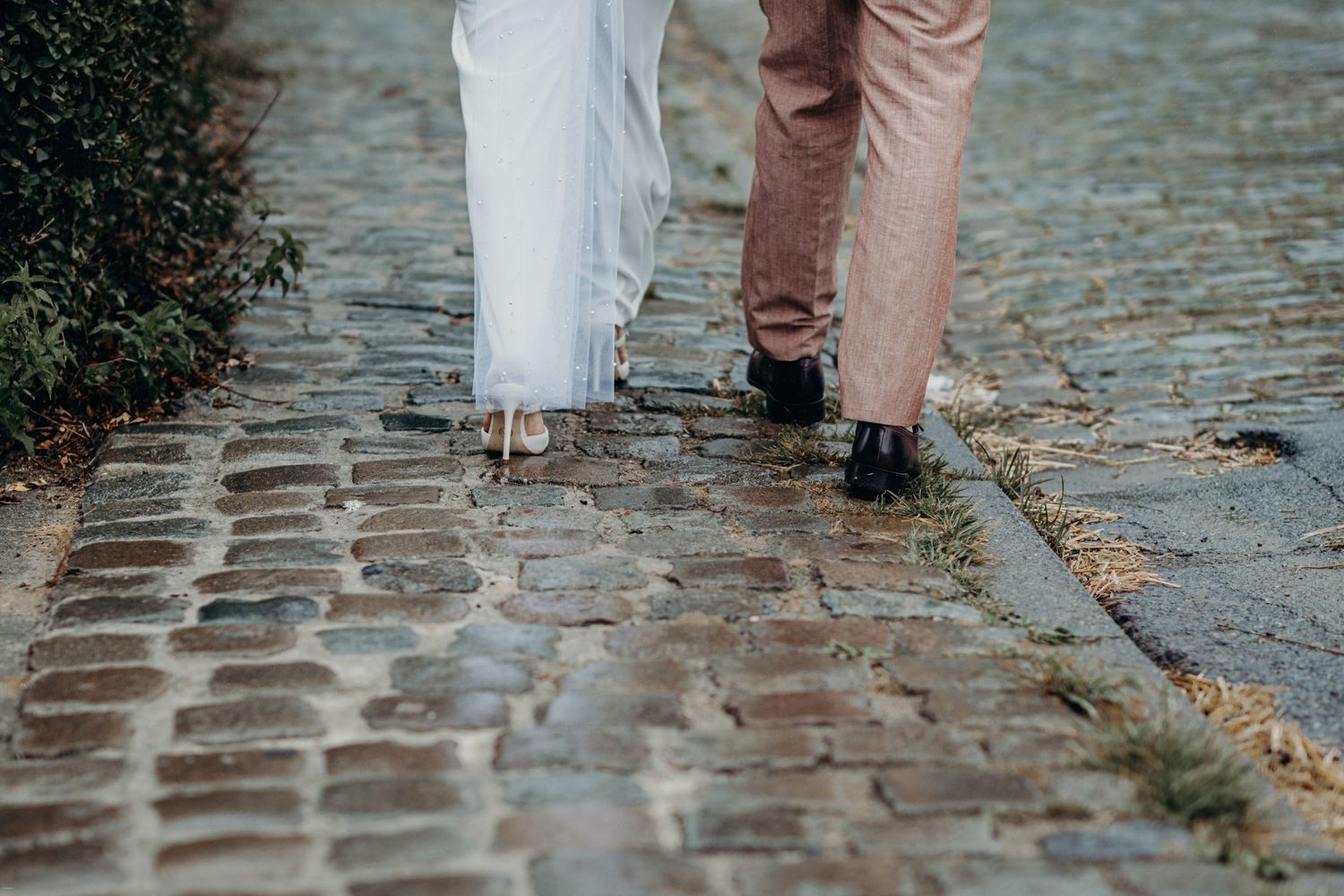 Couple walking together on wet cobblestone streets.