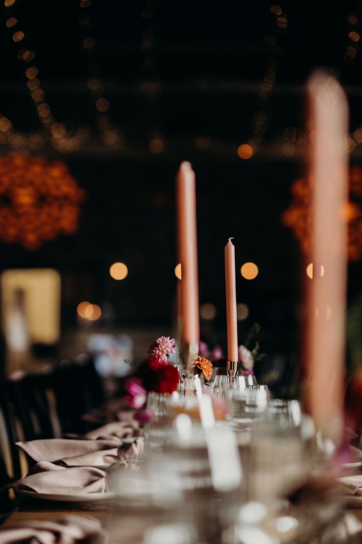 Elegant wedding reception table setting with tall white candles and soft lighting.