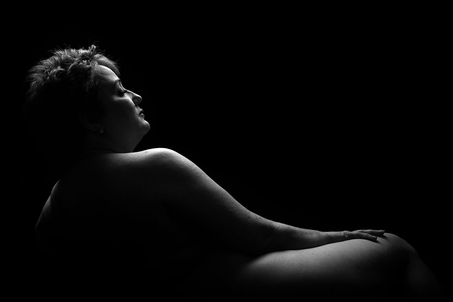 Elegant black-and-white boudoir portrait in a Charlotte studio featuring a woman with stylized lighting.