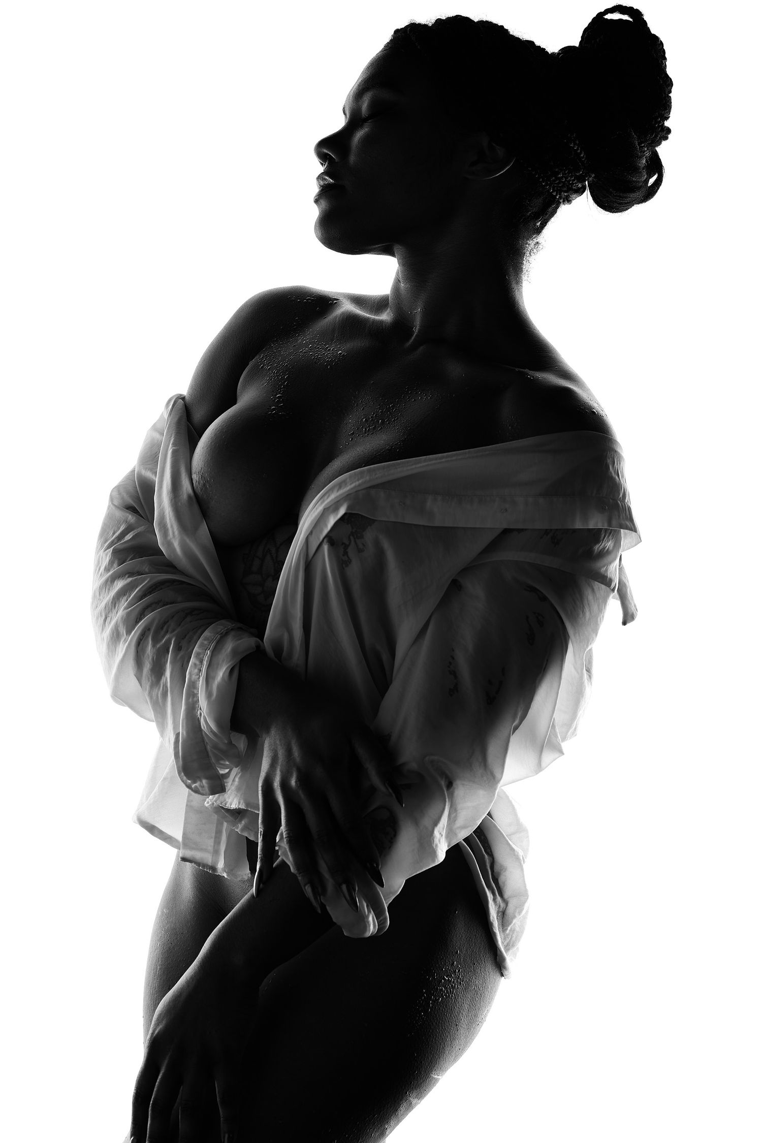 Black and white boudoir photography in Charlotte featuring a woman in a wet white shirt with soft, artistic lighting.