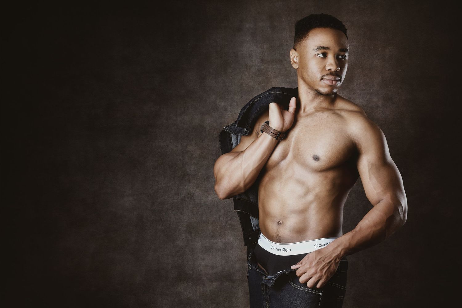 Shirtless man holding a jacket over his shoulder during a luxury men's boudoir photoshoot in Charlotte, NC.