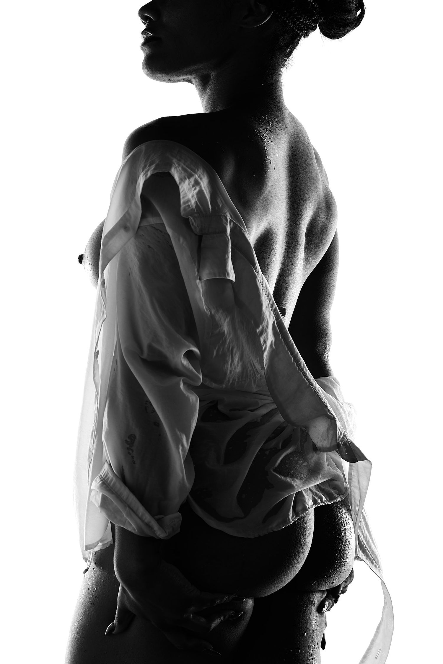Sexy boudoir photography in Charlotte featuring a woman in a wet white shirt with soft, artistic lighting.