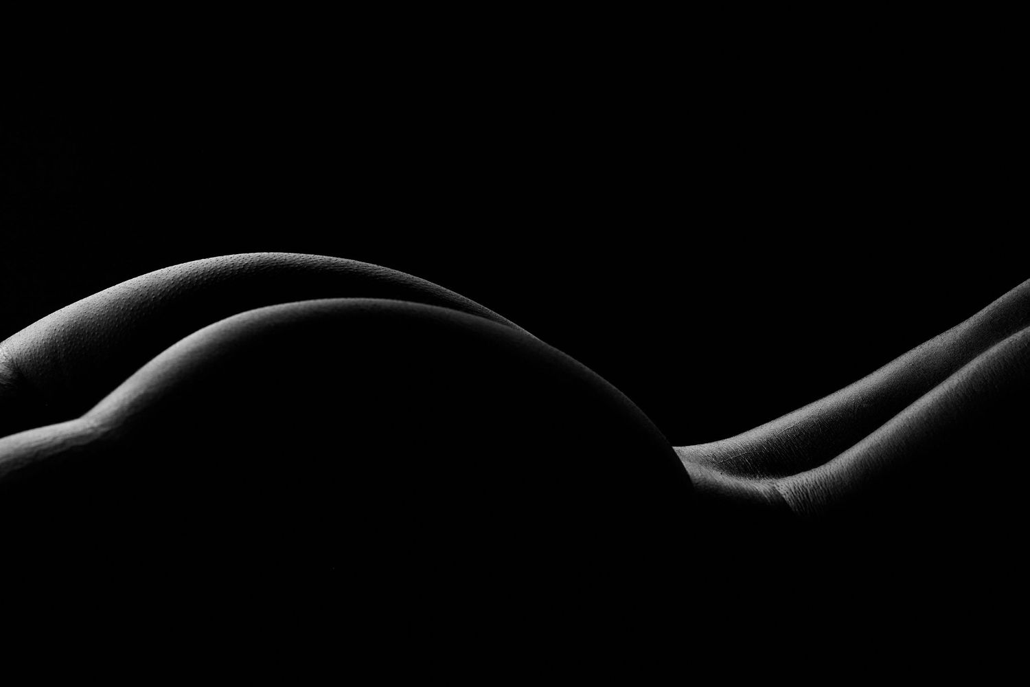 Sensual body scape boudoir portrait in a Charlotte studio featuring a woman with moody lighting.
