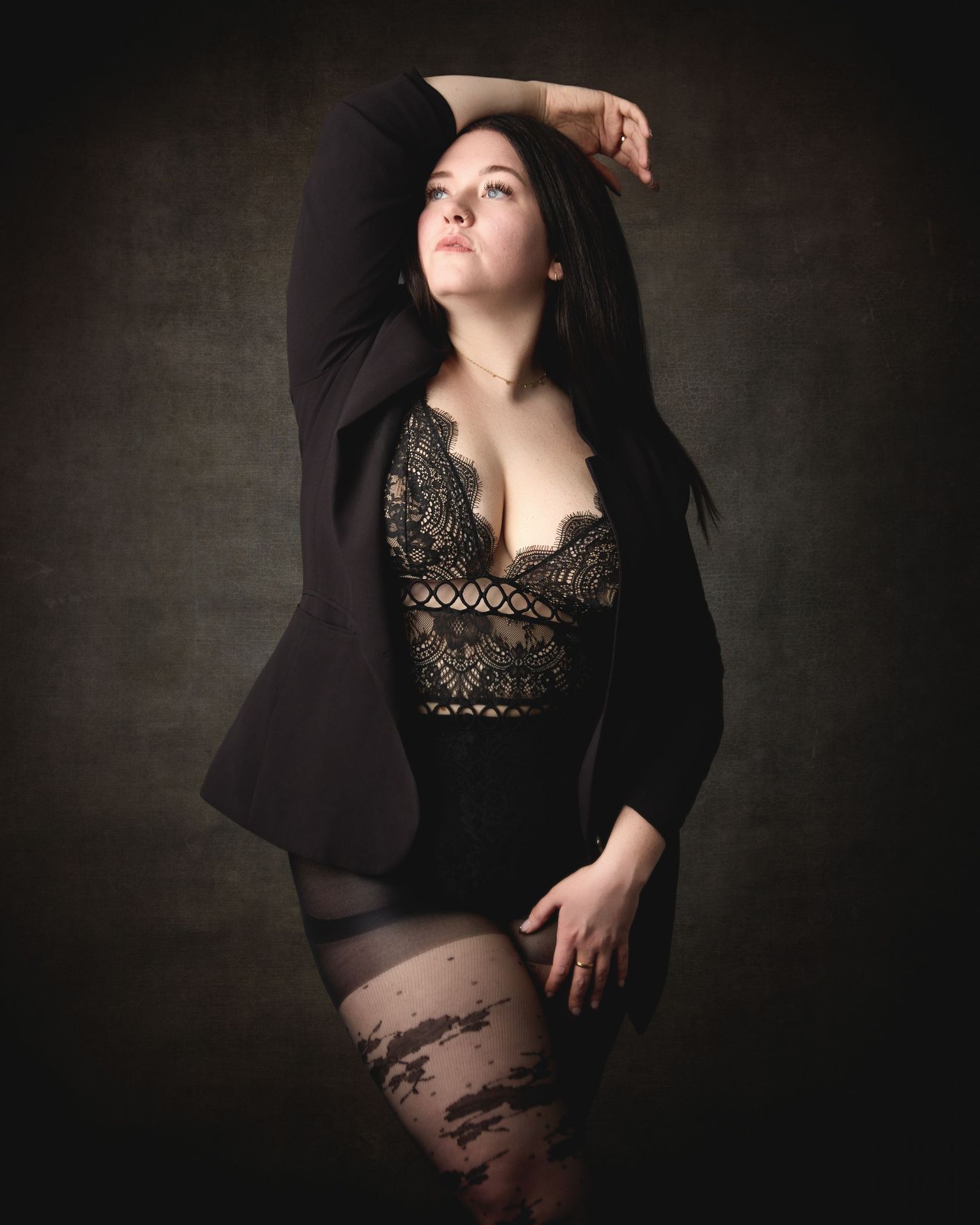 Luxury boudoir photoshoot in Charlotte, featuring dramatic lighting and black lace attire against a dark background.