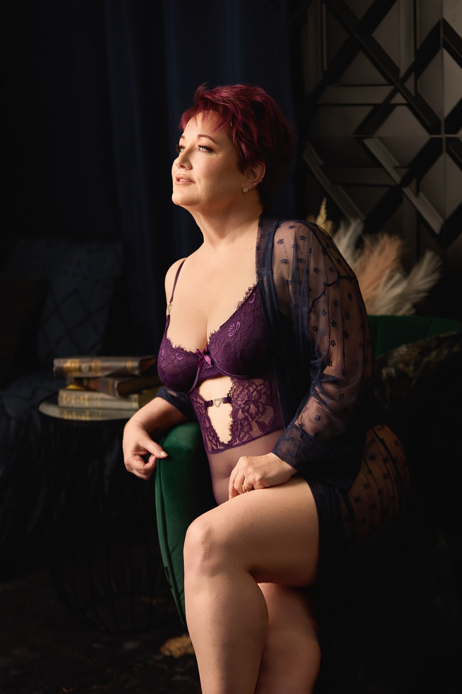 A woman in purple lingerie sitting on a vintage-style chair, featuring professional editorial lighting at a Charlotte boudoir studio.