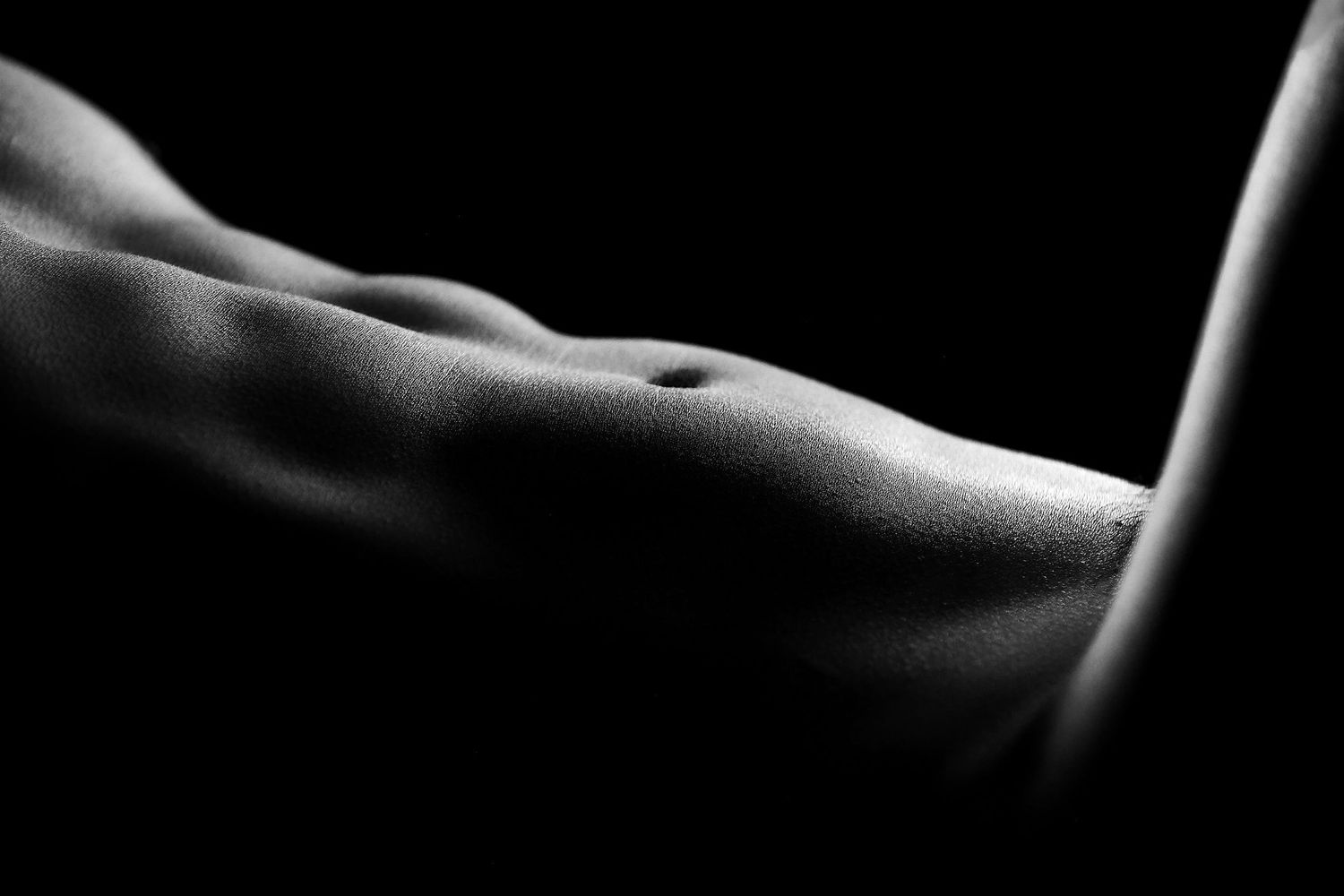 Black and white male physique photography featuring highlights and shadows for body sculpting.