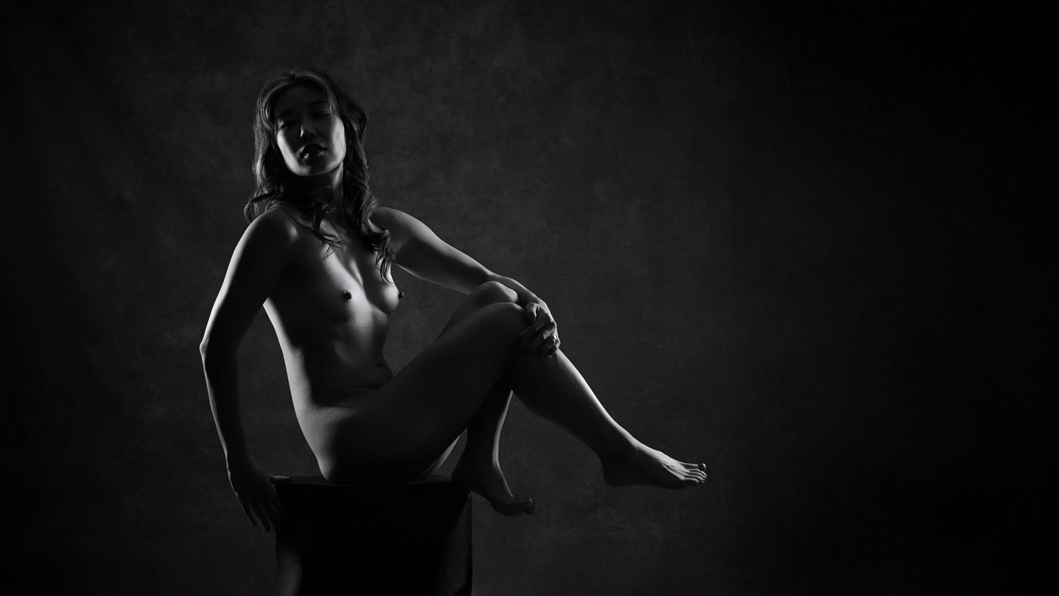 Fine-art nude boudoir black and white portrait featuring dramatic poses in low-key lighting.