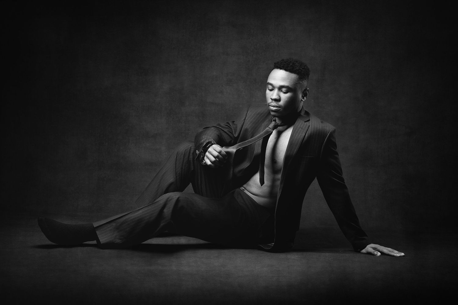 Sleek male portrait with high-contrast studio lighting emphasizing muscle tone and contemporary men's style.