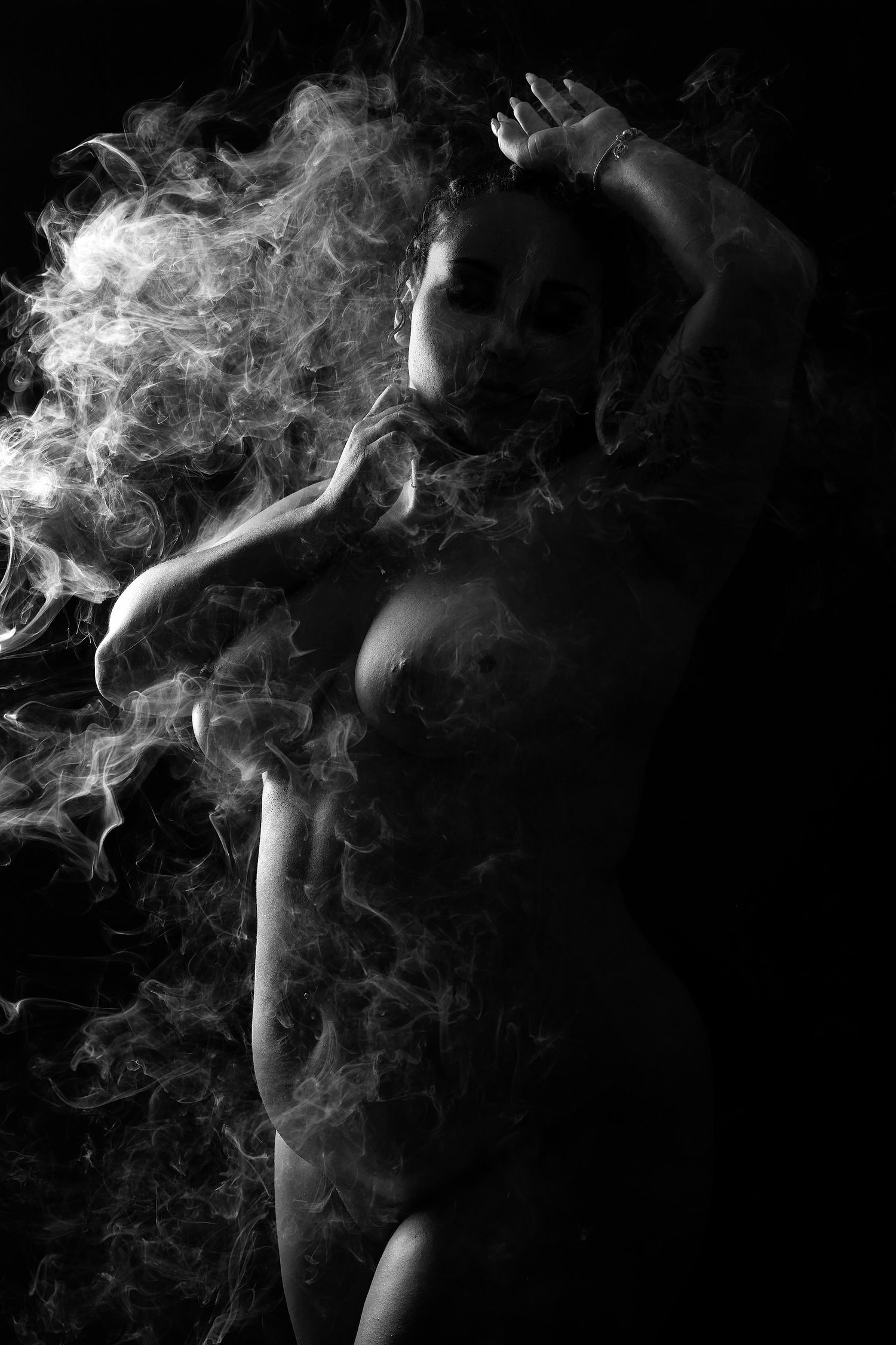 Editorial-style sensual portrait emphasizing beautiful lines and rich shadows with smoke in Matthews, NC.
