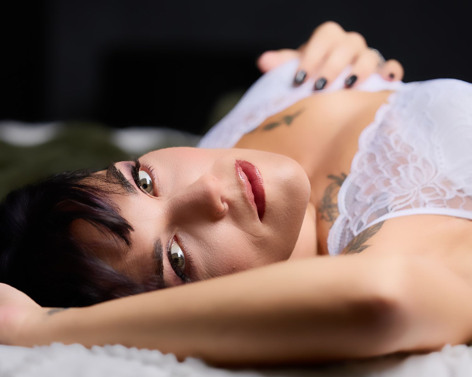Intimate close-up boudoir portrait of a woman with short dark hair wearing white lace lingerie under soft studio lighting in Concord, NC.