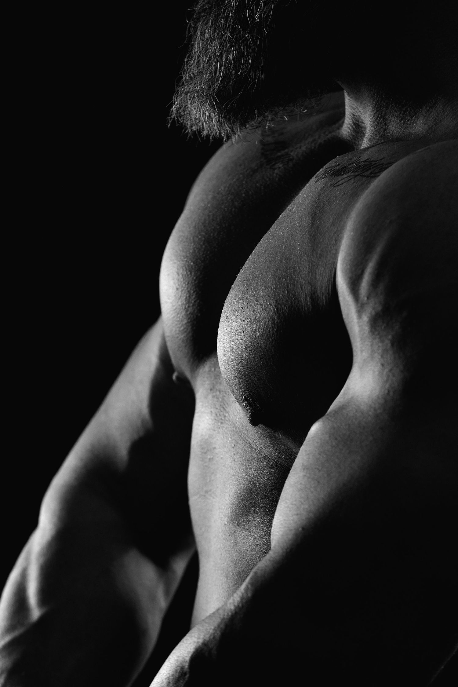 Black and white boudoir image of a male figure in dramatic lighting.