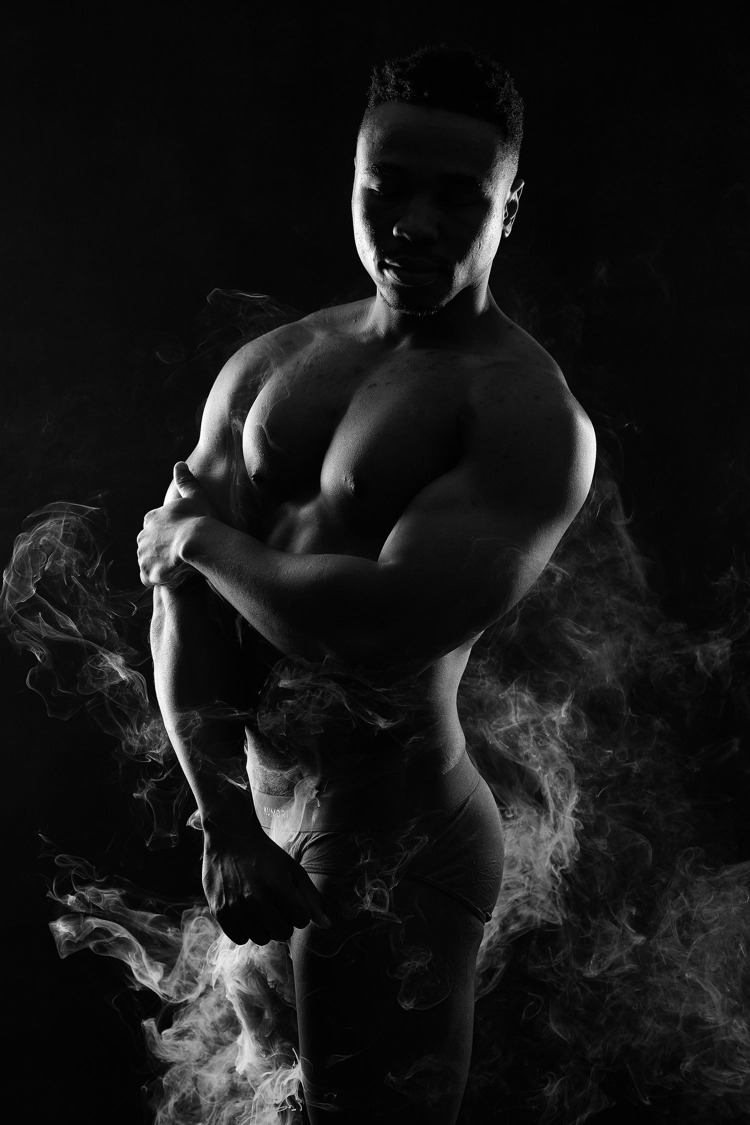 Sleek male portrait with high-contrast studio lighting emphasizing muscle tone and contemporary men's style.