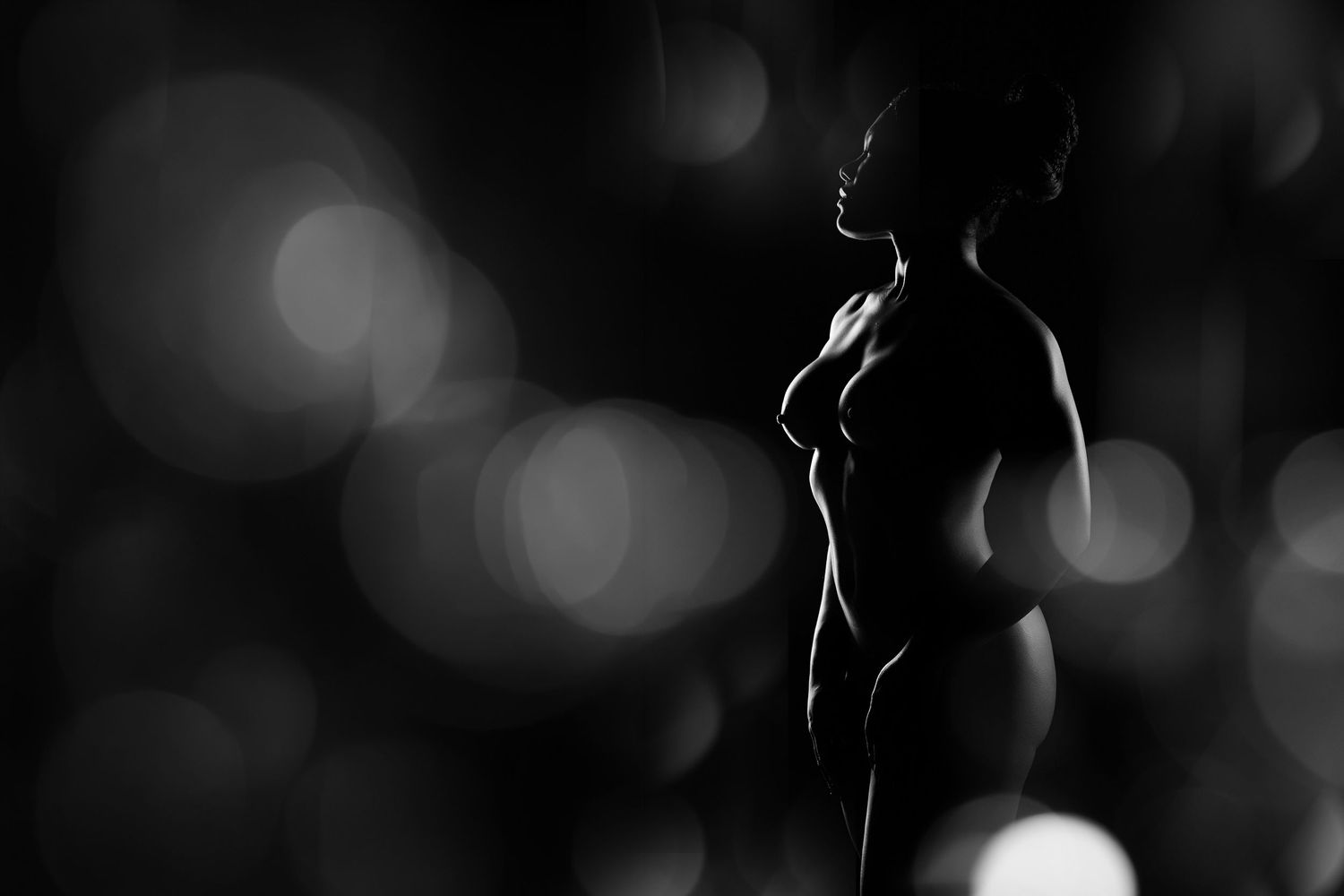 High-contrast silhouette boudoir photography in Charlotte with artistic bokeh and dramatic studio lighting.