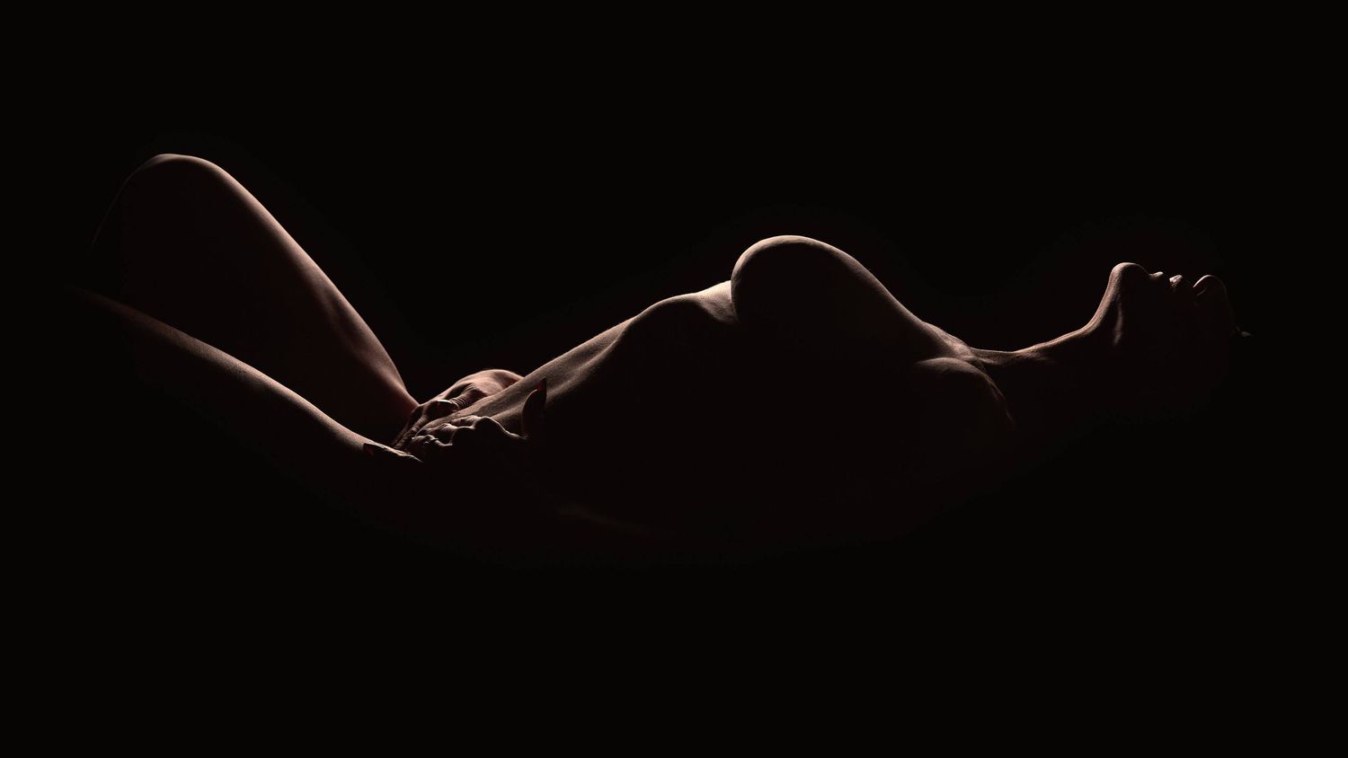 Luxury Charlotte boudoir photography with guided posing and editorial lighting of a woman's full body silhouette.