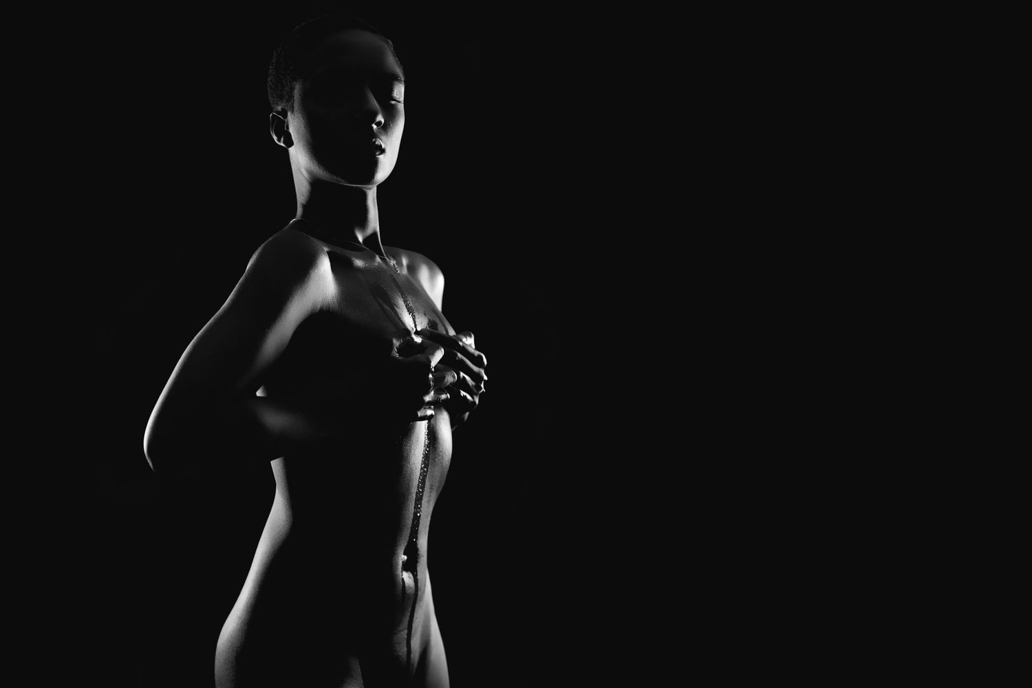 Dramatic black and white silhouettes of a person in different poses against a dark background in a boudoir studio.