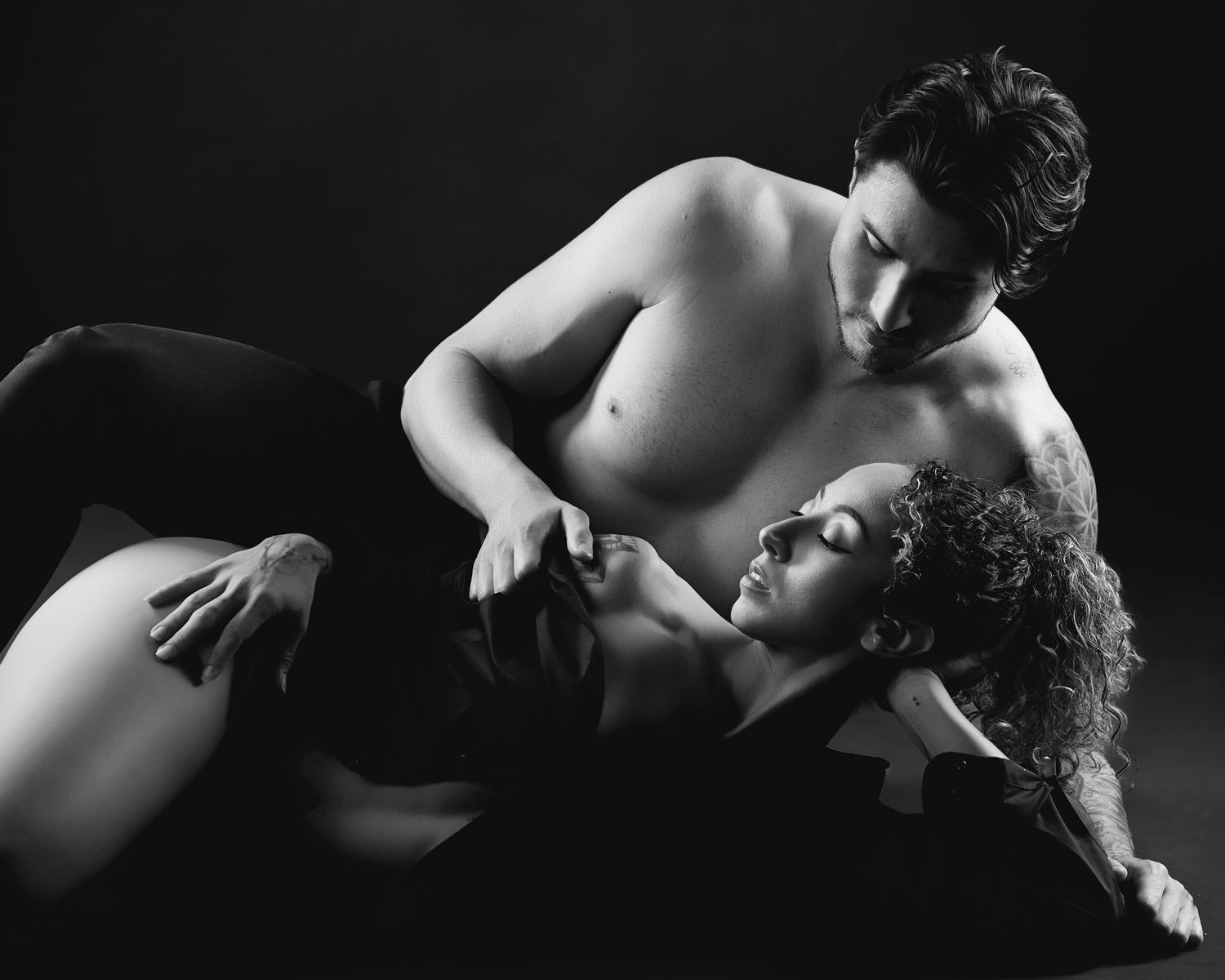 Luxury boudoir photography in Charlotte featuring a couple in a romantic, intimate pose with editorial lighting.