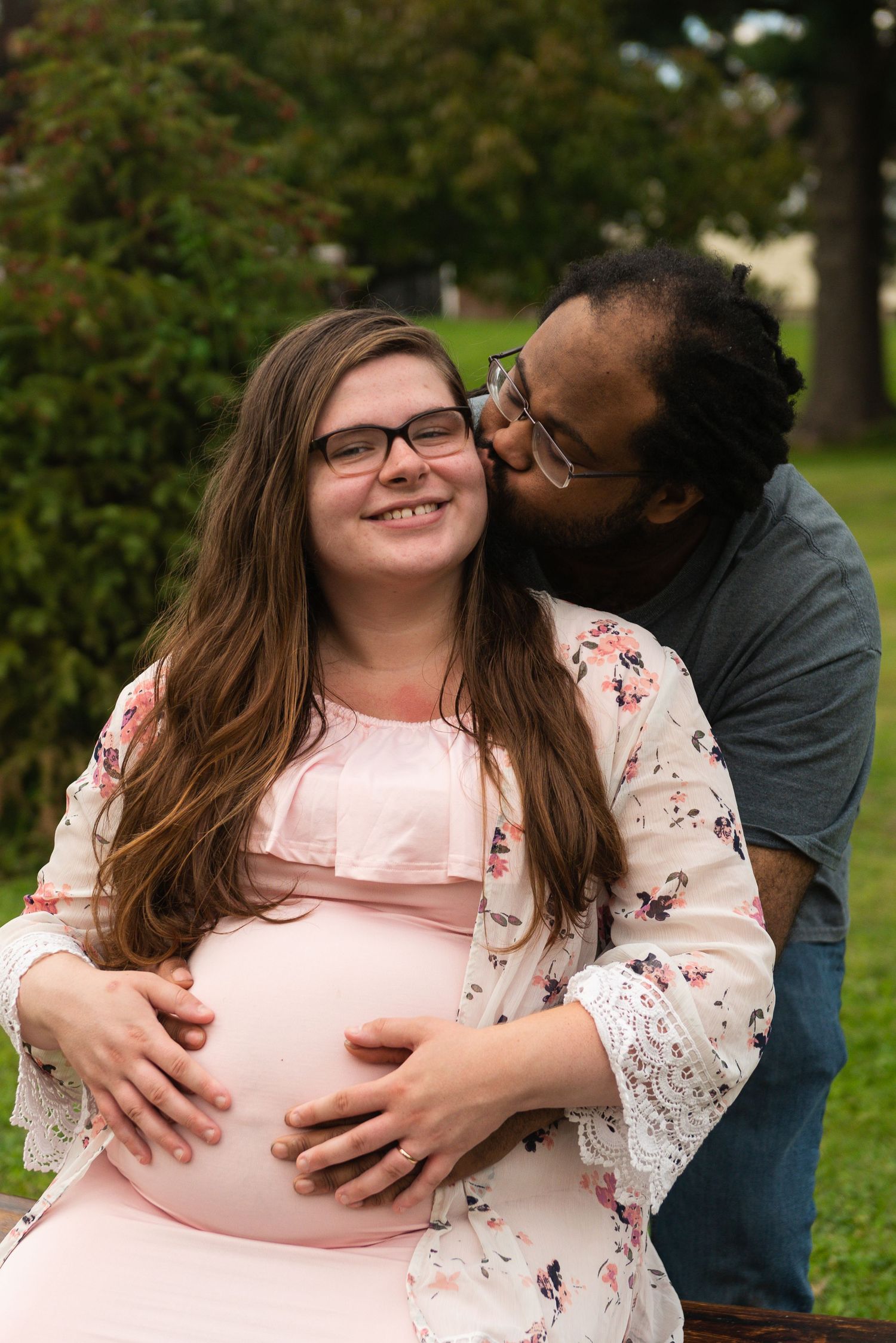Sweet maternity session showing tender moments outdoors in a park setting.