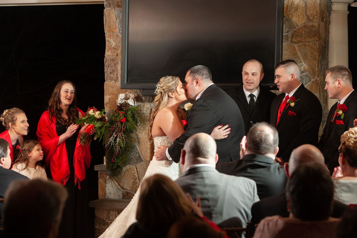 Wedding ceremony guests gathered in rustic venue with stone walls.